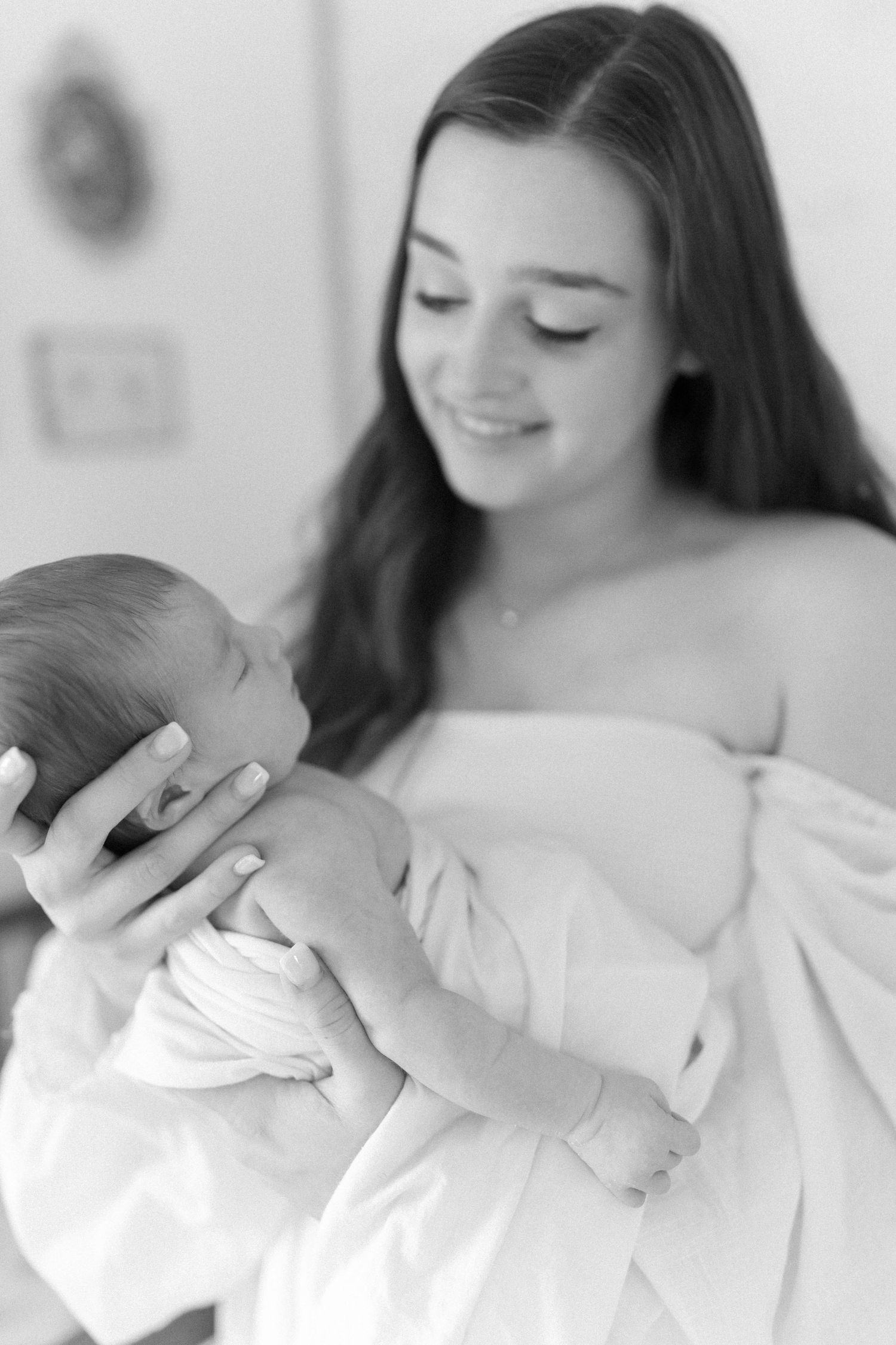 Black and white portrait of mother cradling newborn baby in gentle embrace.