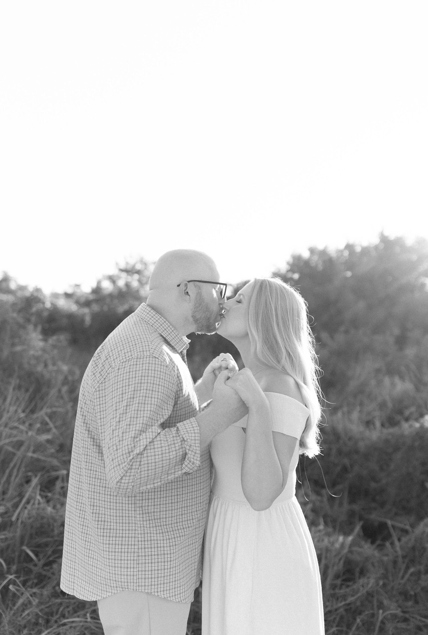 Black and white portrait of couple sharing intimate moment in outdoor setting.