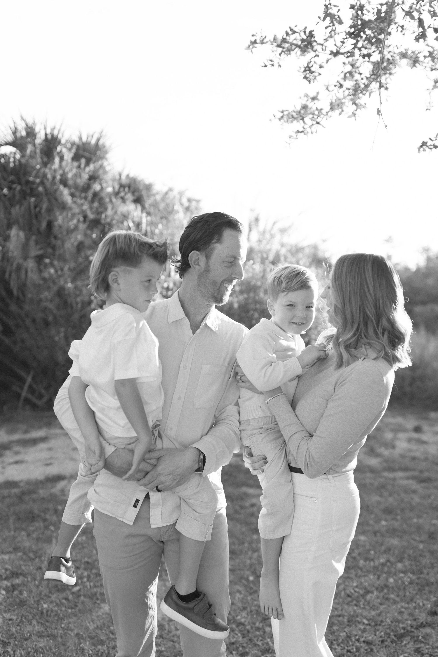 Black and white portrait of a family sharing a close moment together outdoors.