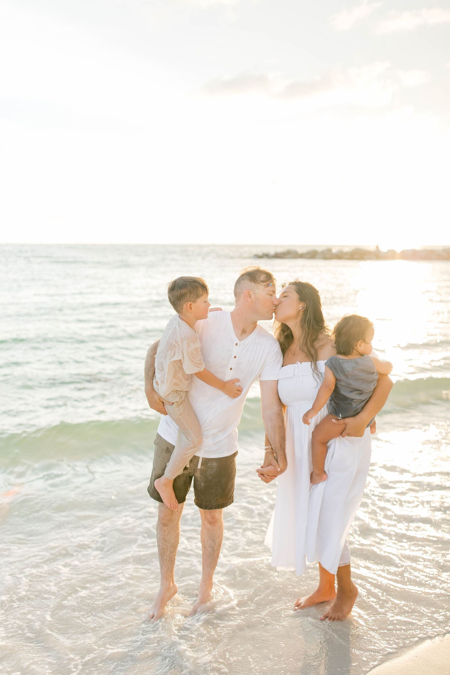 Family members sharing intimate moments while playing on the beach at sunset.