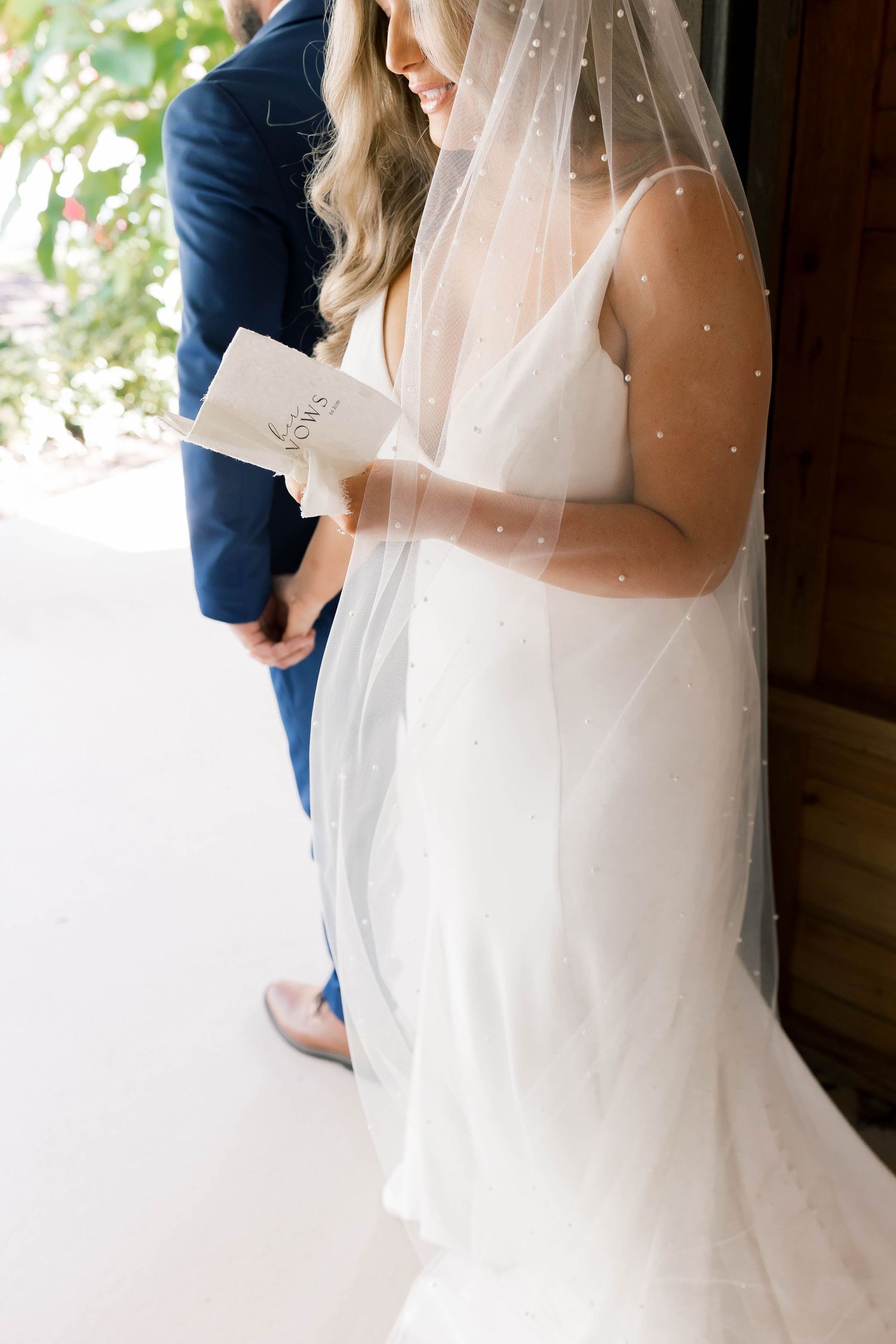 Bride in sparkling veil and white dress during first look moment.