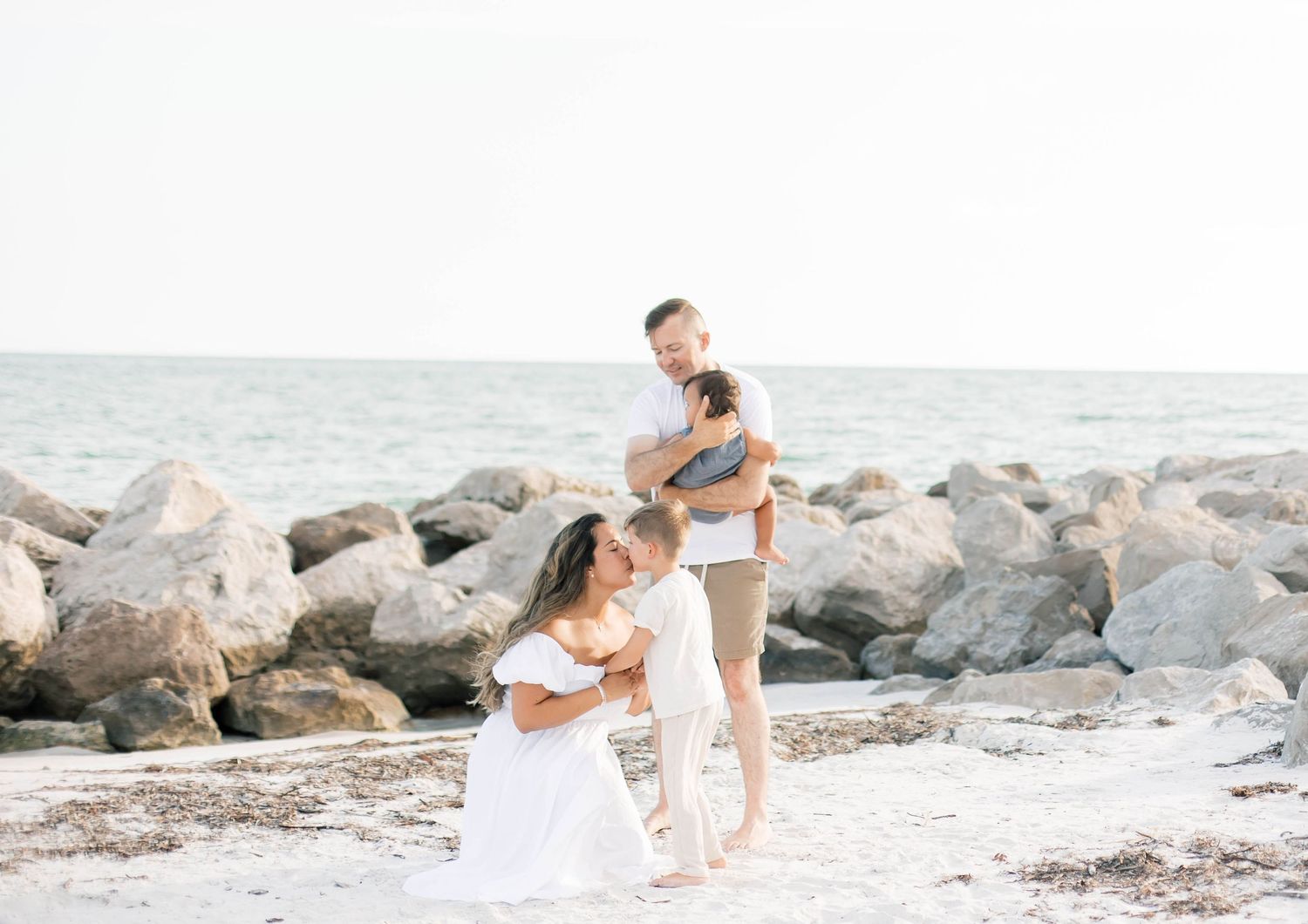 Group poses casually on rocky beach during sunset photoshoot.