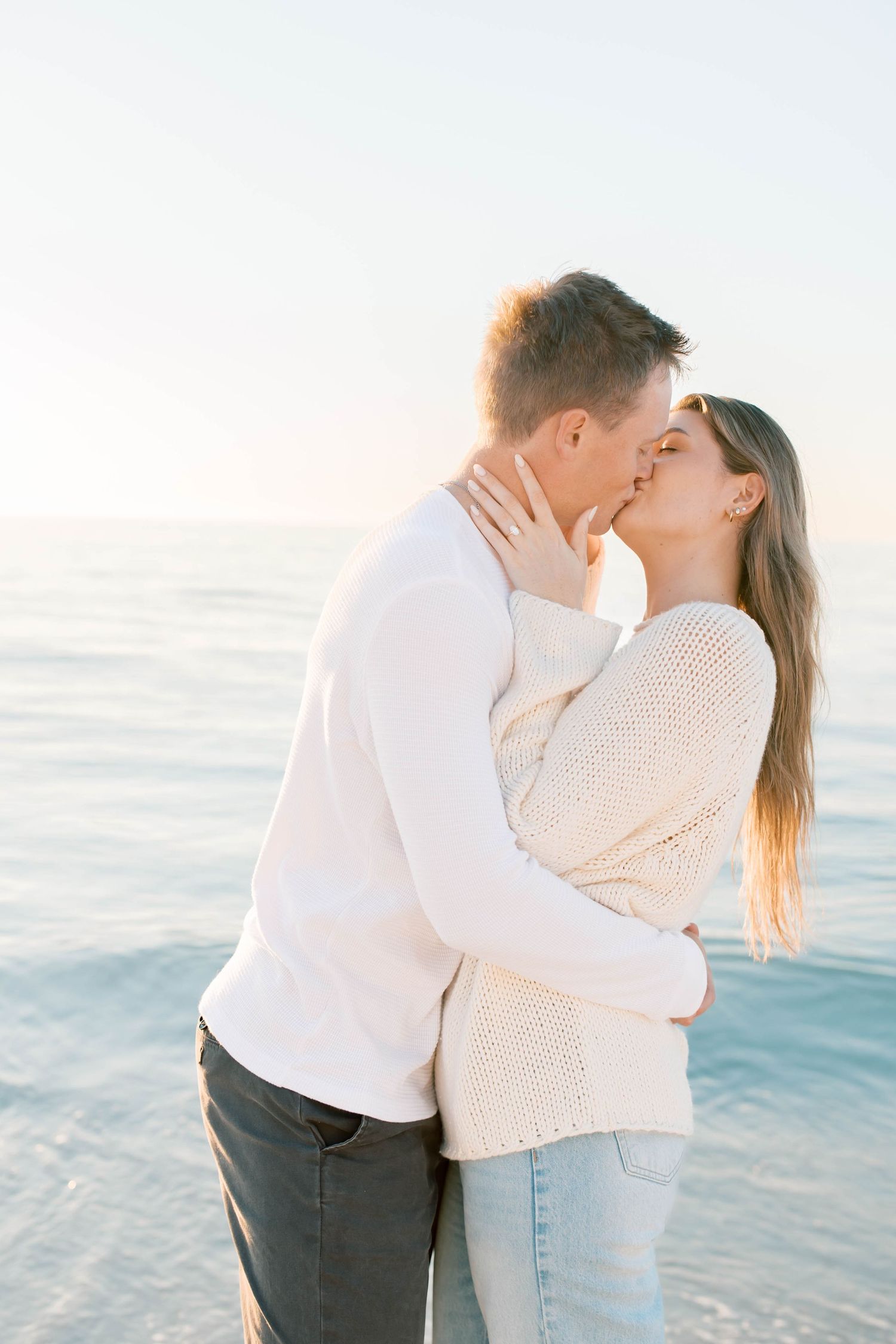 A romantic moment shared between a couple on a beach with gentle waves in the background.