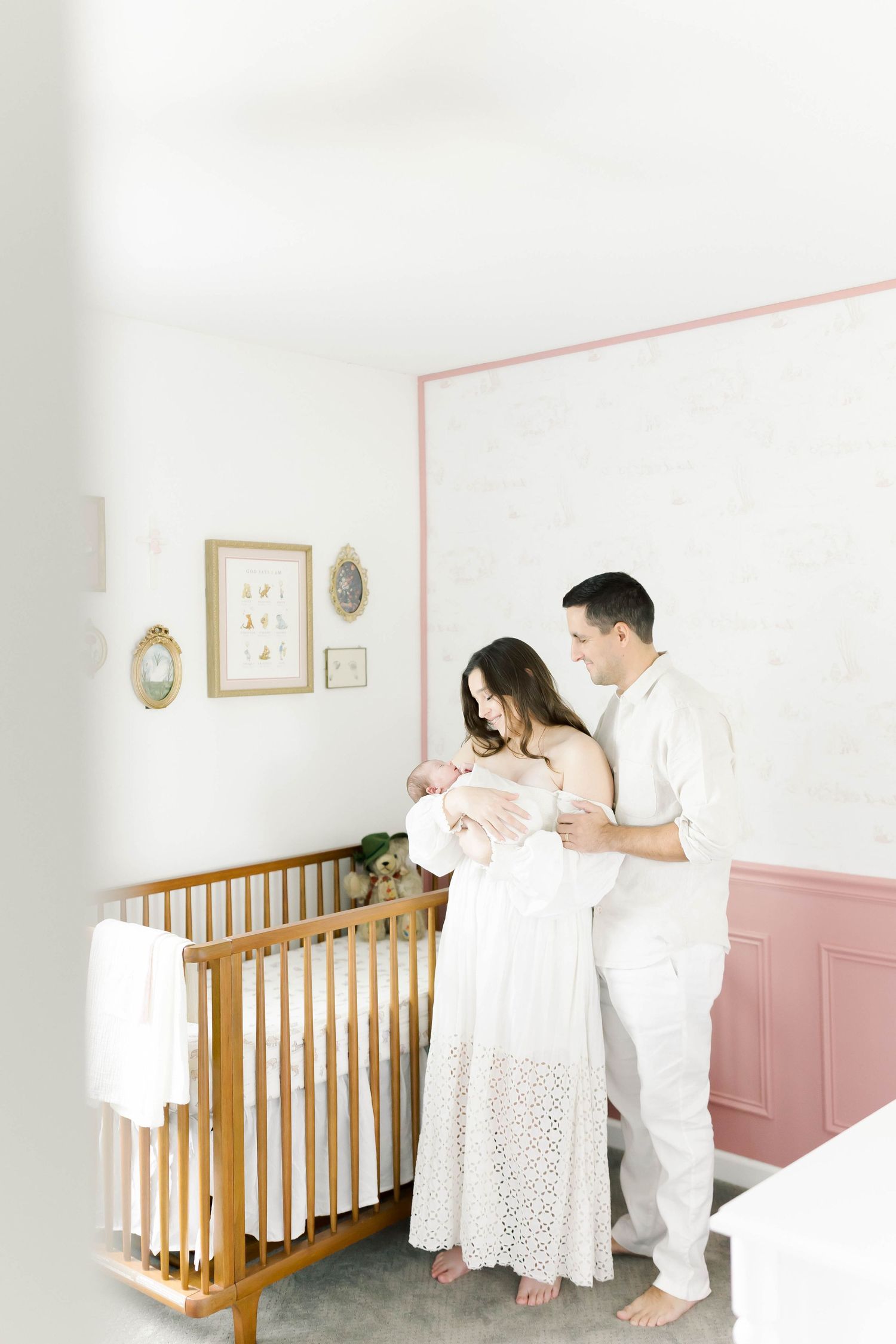 Beautiful nursery scene with wooden crib and pink wainscoting.