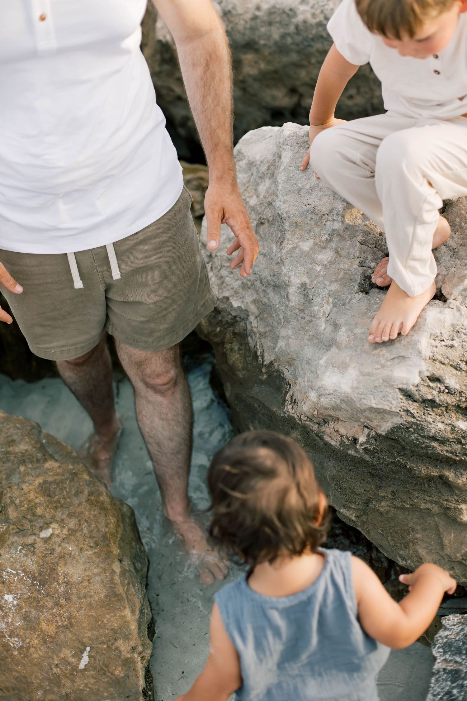 Close-up view of people climbing on large coastal rocks near the ocean.
