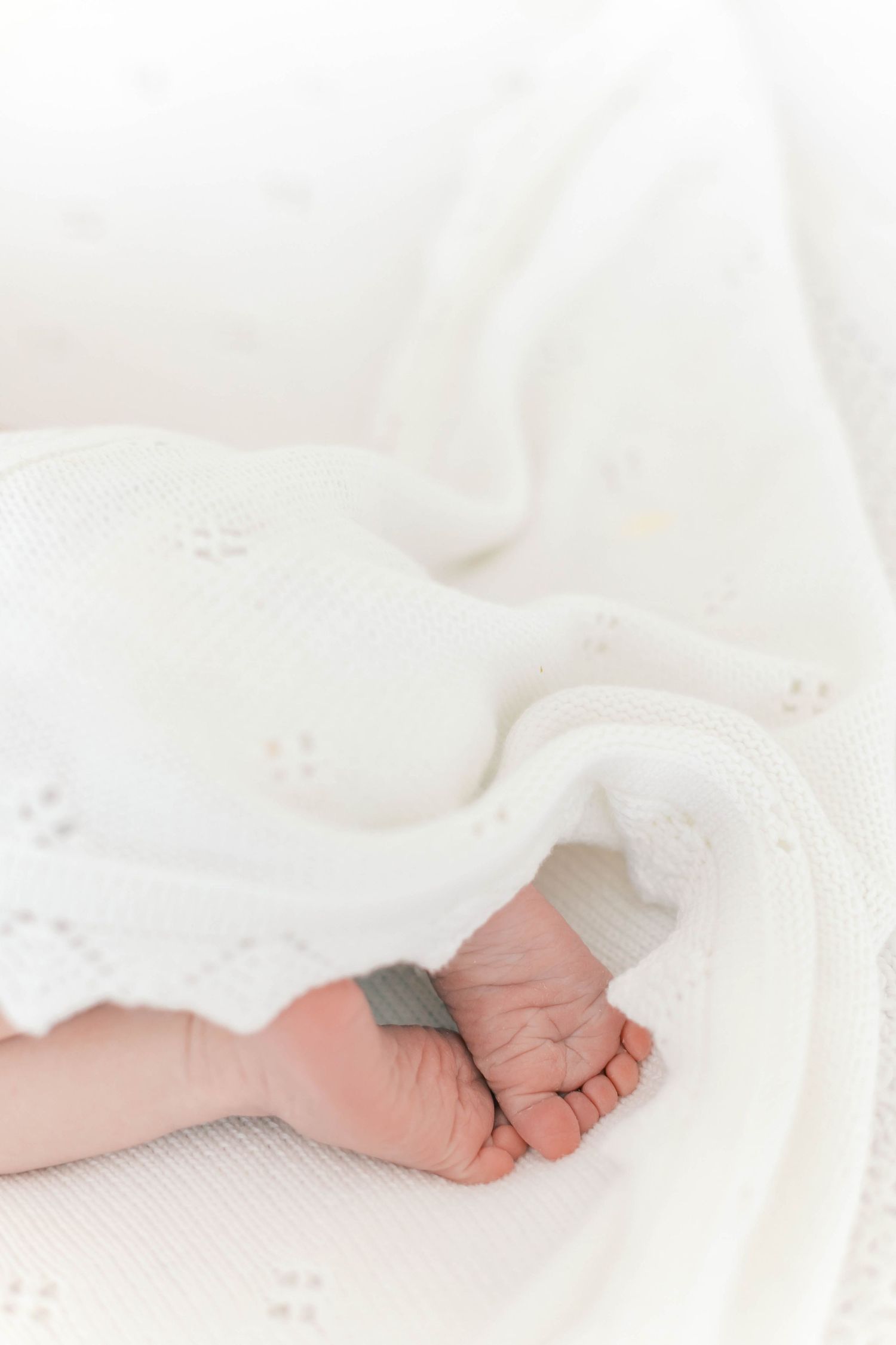Close-up of tiny baby feet against soft white textured fabric.