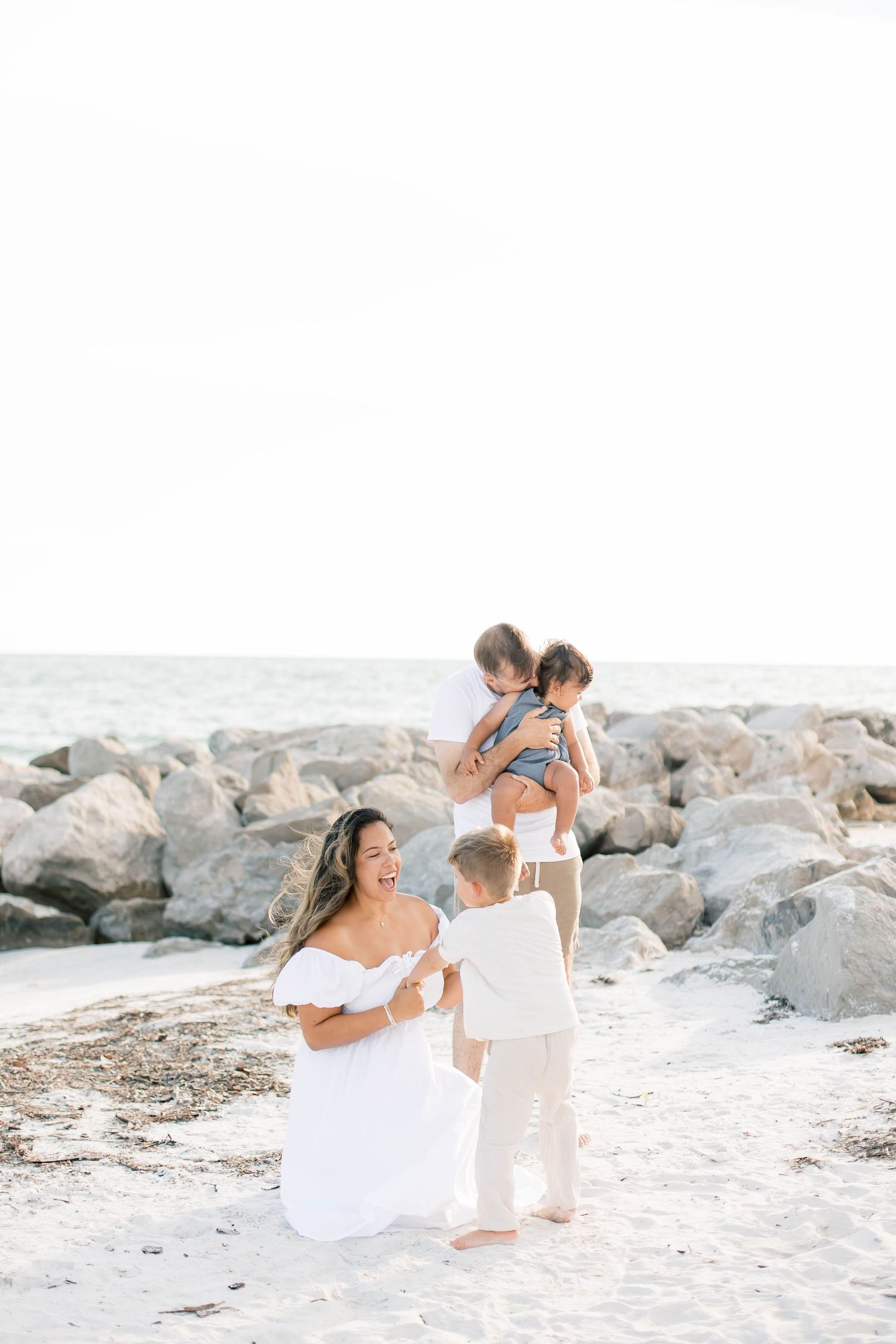 Joyful family moments captured against coastal rocks and ocean waves.