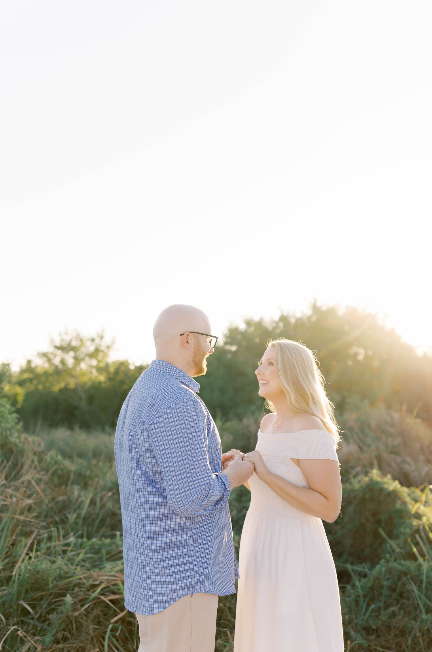 Couple sharing special moment in white dress and blue shirt during sunset proposal.