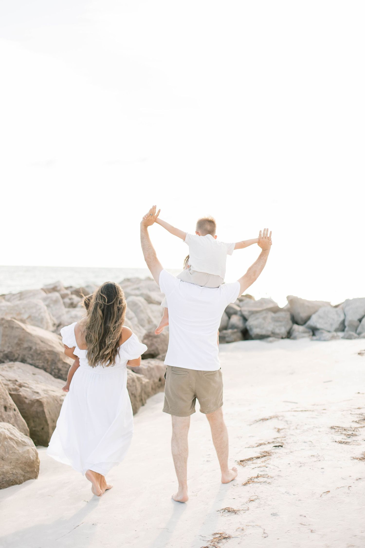 Family members walking with arms raised in celebration on a sunny beach.