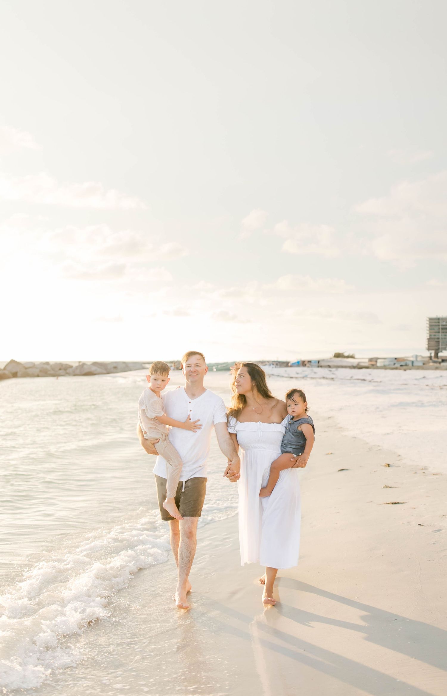 Carefree family walking along the shoreline during golden hour at the beach.