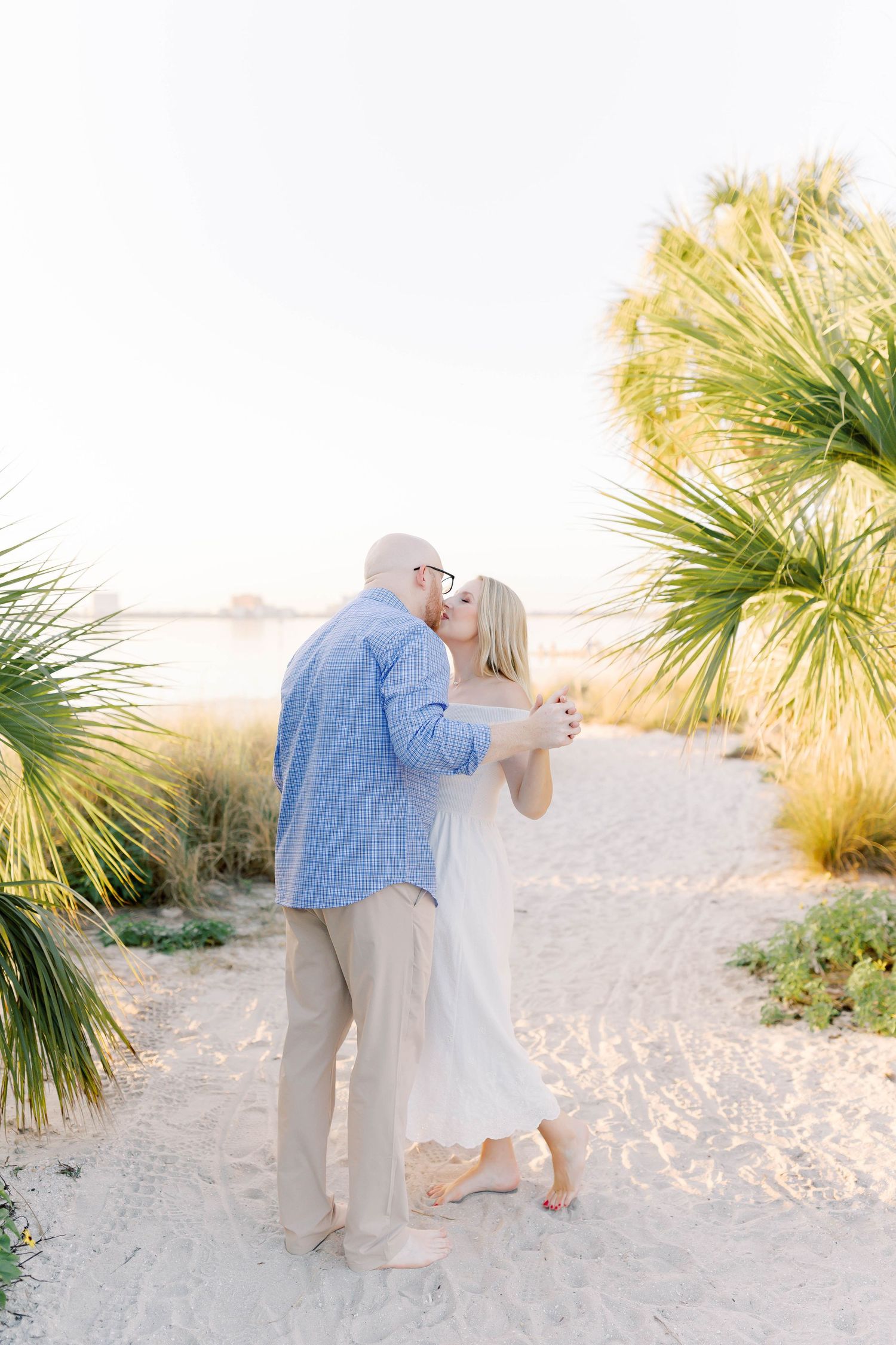 Romantic beach photography session with palm trees and soft lighting.