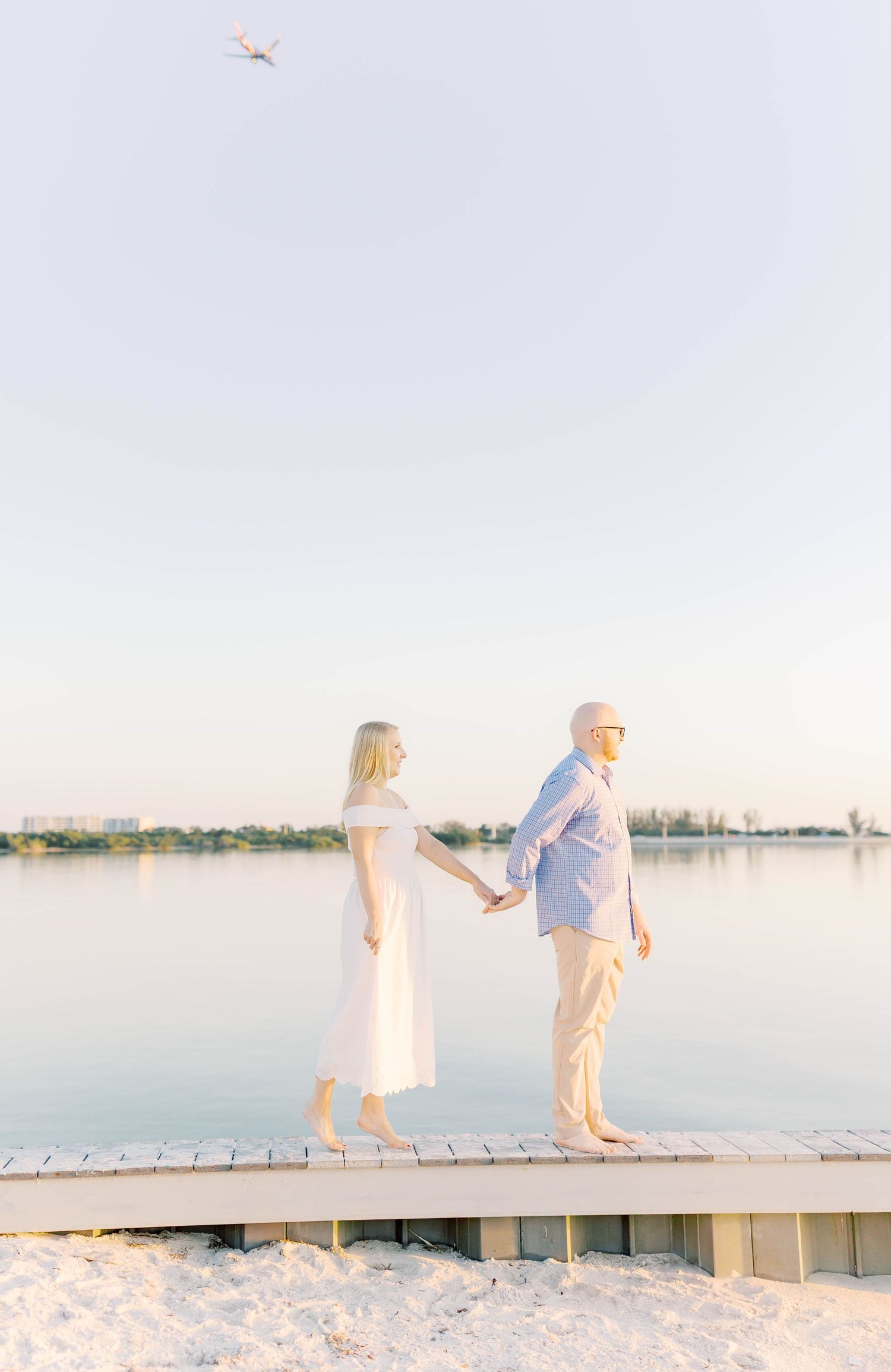 Couple walking together on sandy beach with waterfront views.