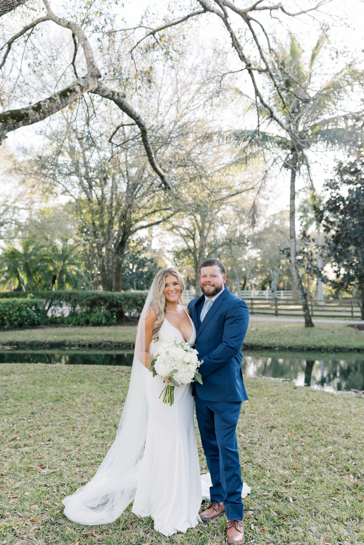 Wedding portrait in lush garden setting with palm trees and pond.