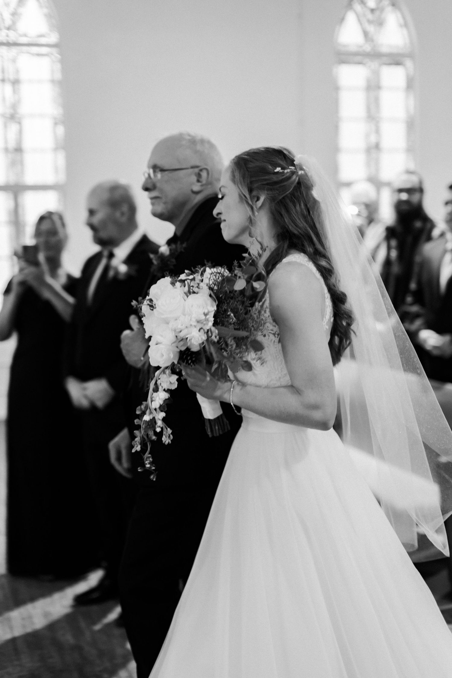 Black and white wedding reception photos showing guests mingling indoors with floral arrangements.