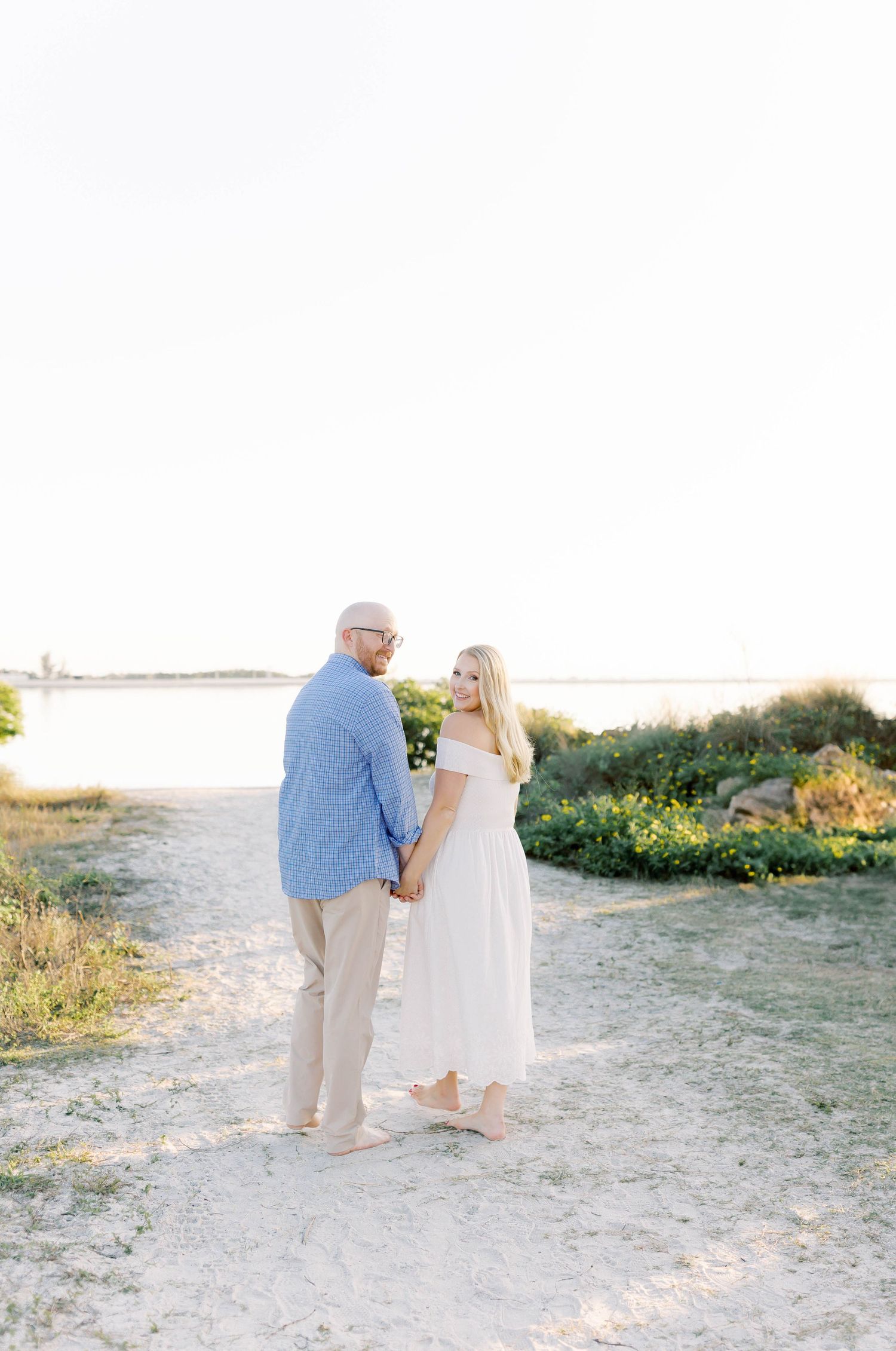 Couple strolling together on sandy coastal path during golden hour.