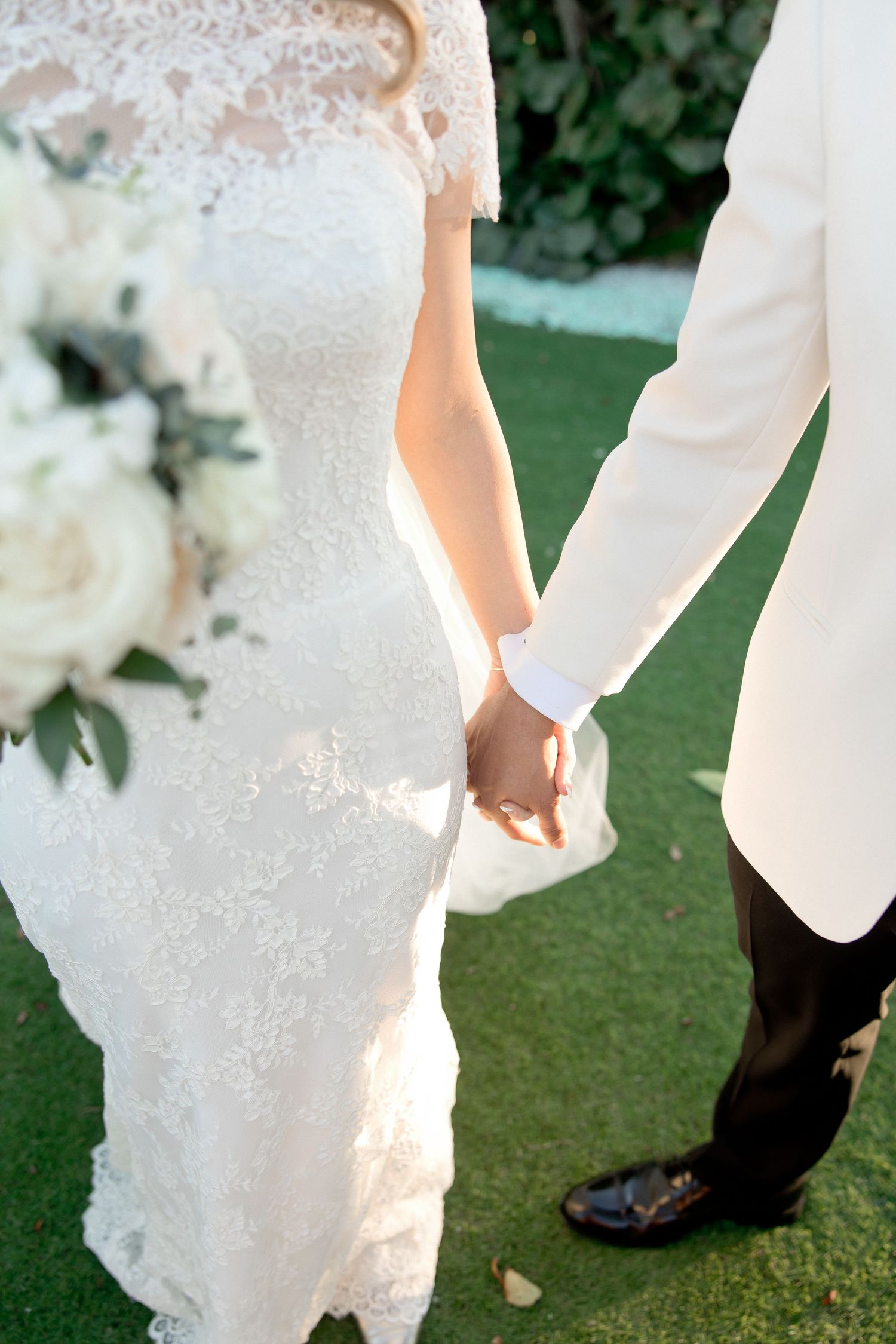 Close-up details of lace wedding dress and formal attire on golf course.