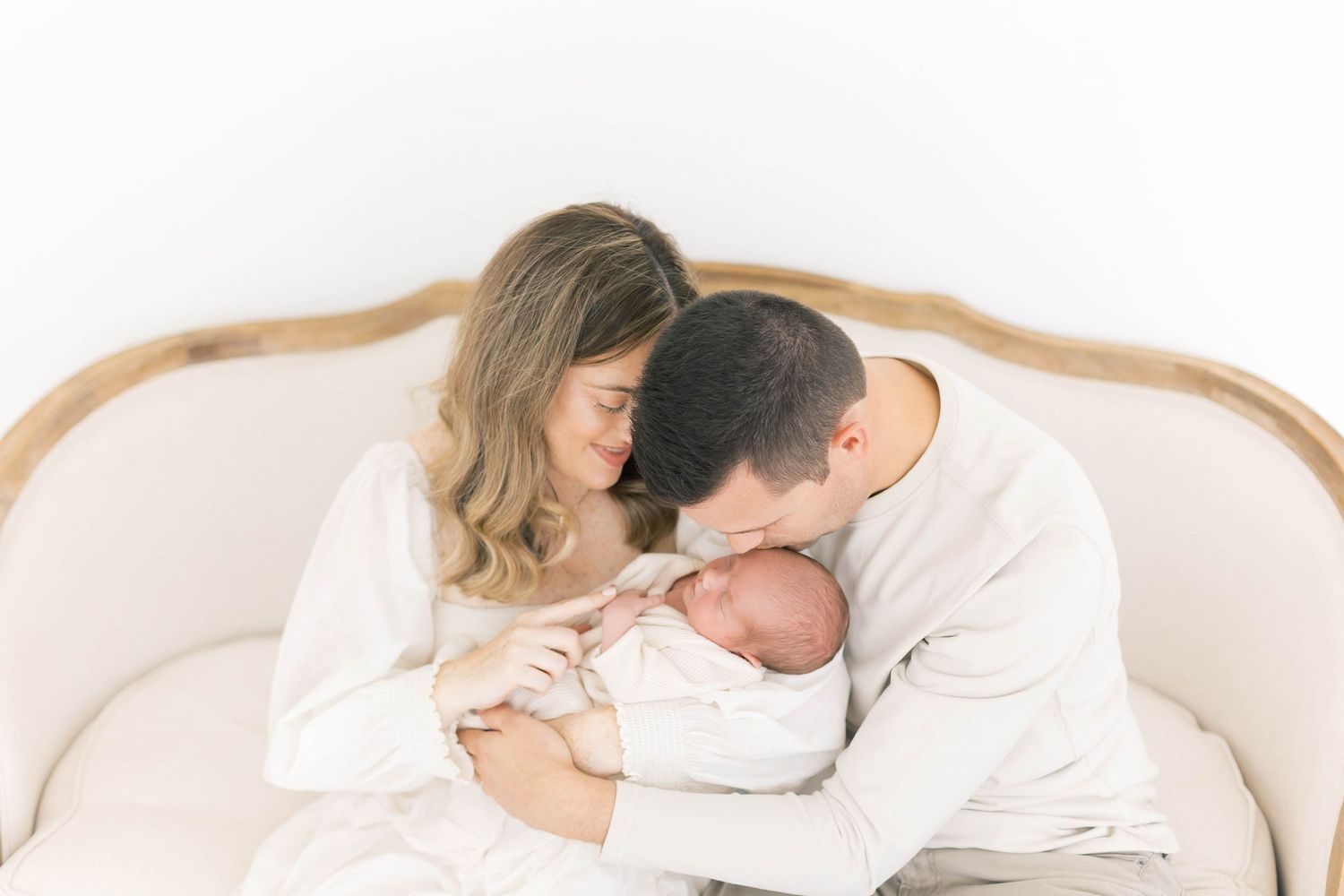 Gentle family moments captured in bright white studio setting.