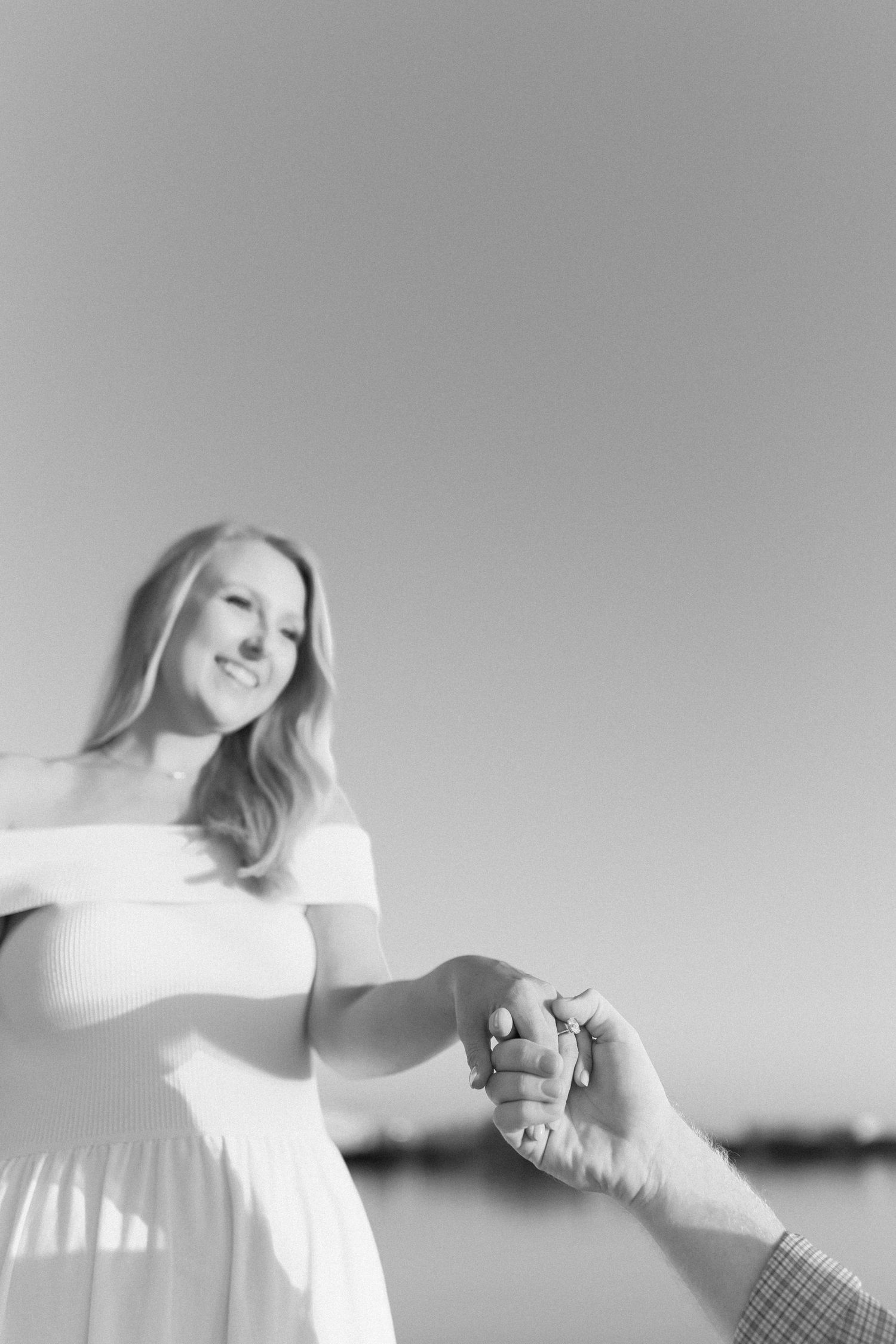 Black and white photo of couple holding hands on dock during engagement session.