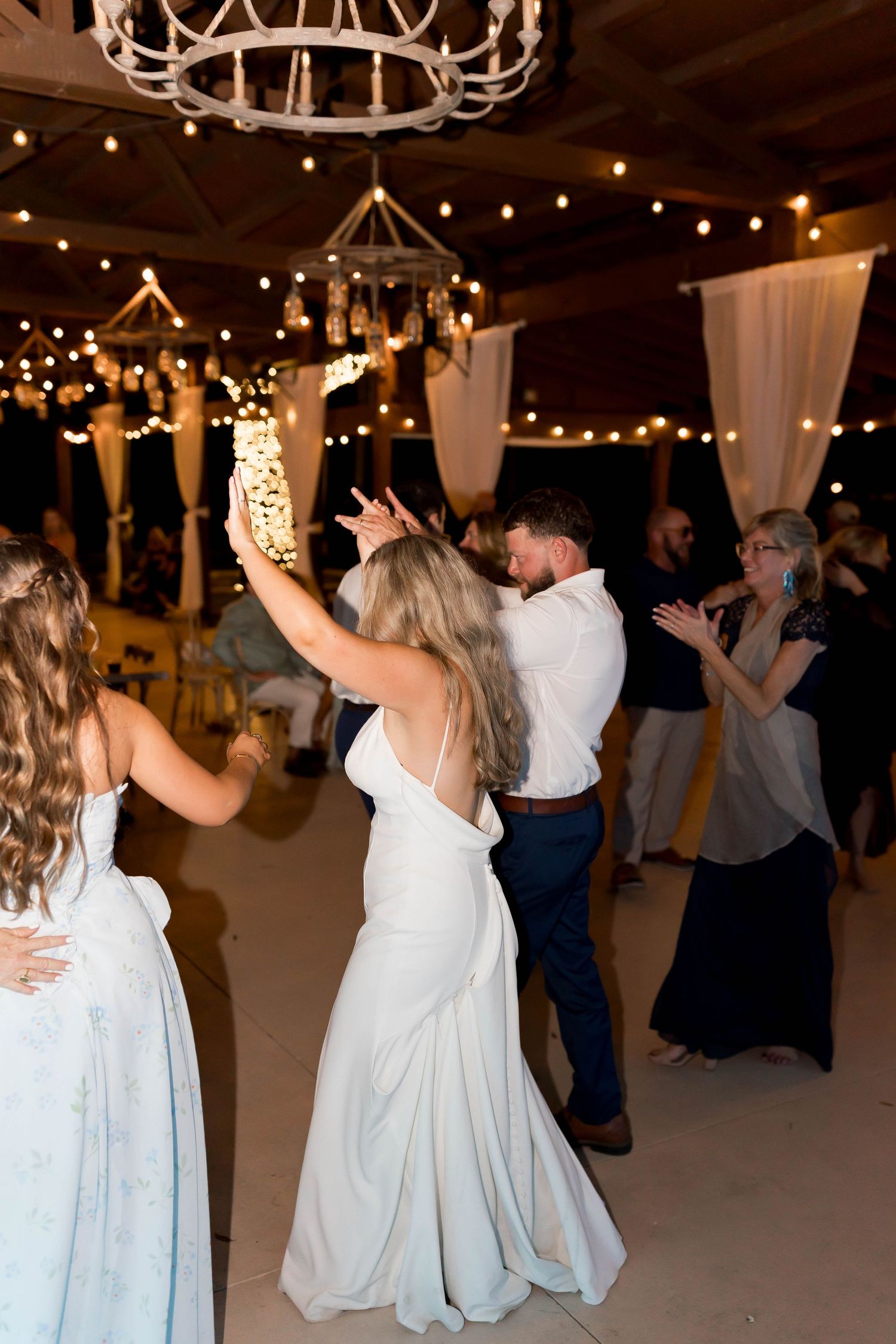 Wedding reception dance floor with string lights and white drapes creating a romantic atmosphere.