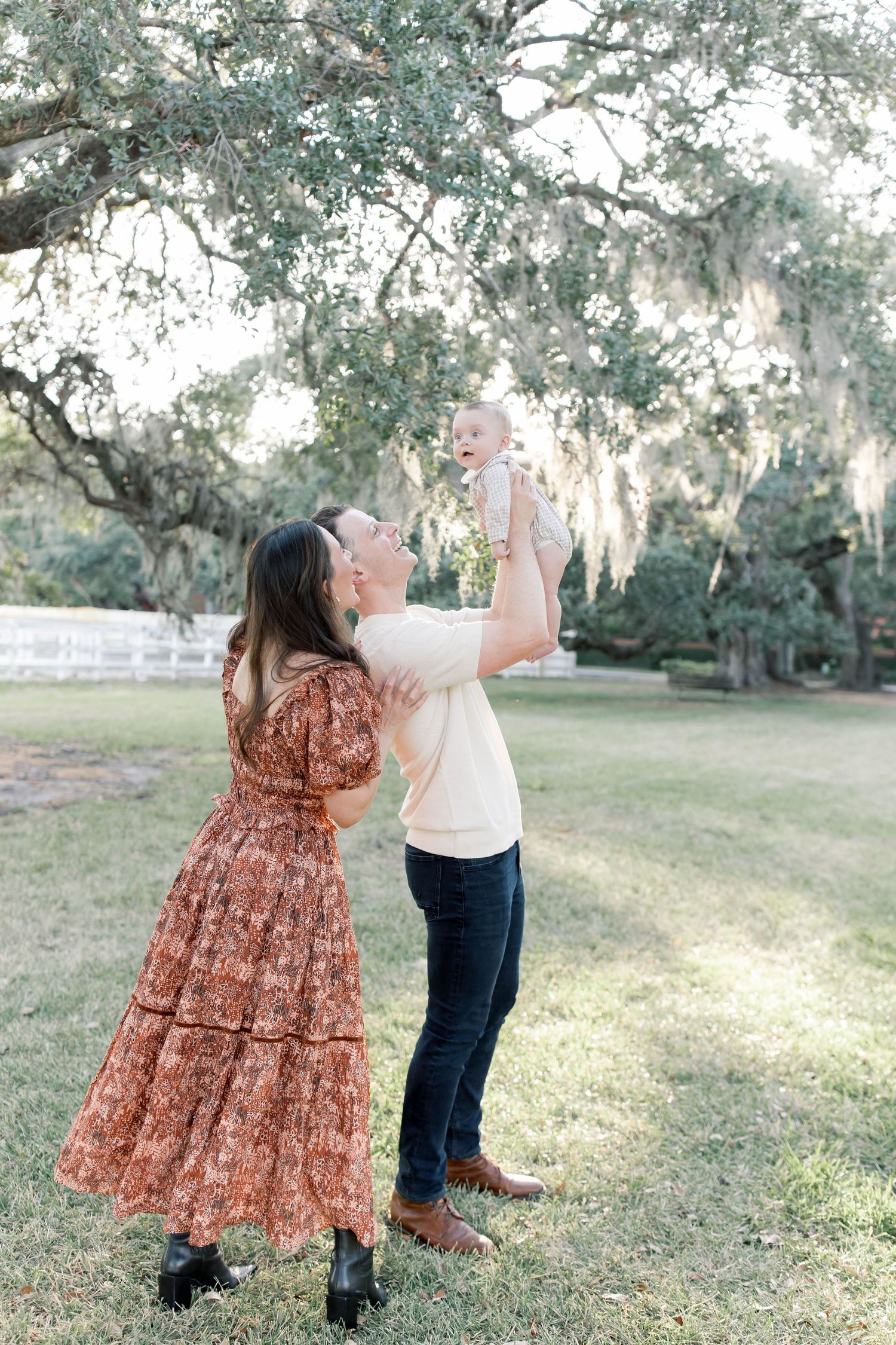 Couple dancing and twirling together under oak trees in a romantic outdoor setting.