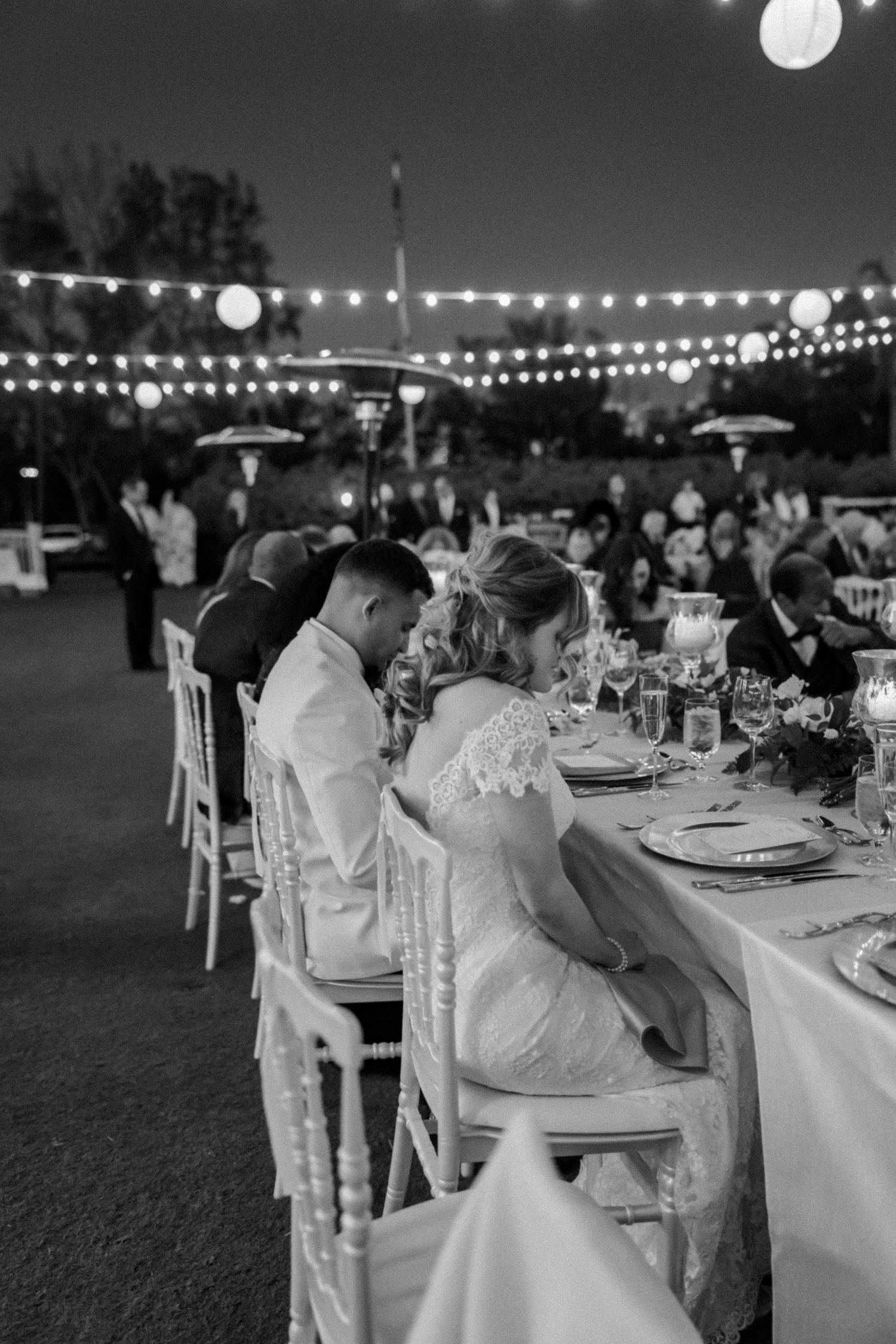 Black and white photos of an outdoor wedding reception with string lights and table settings at dusk.