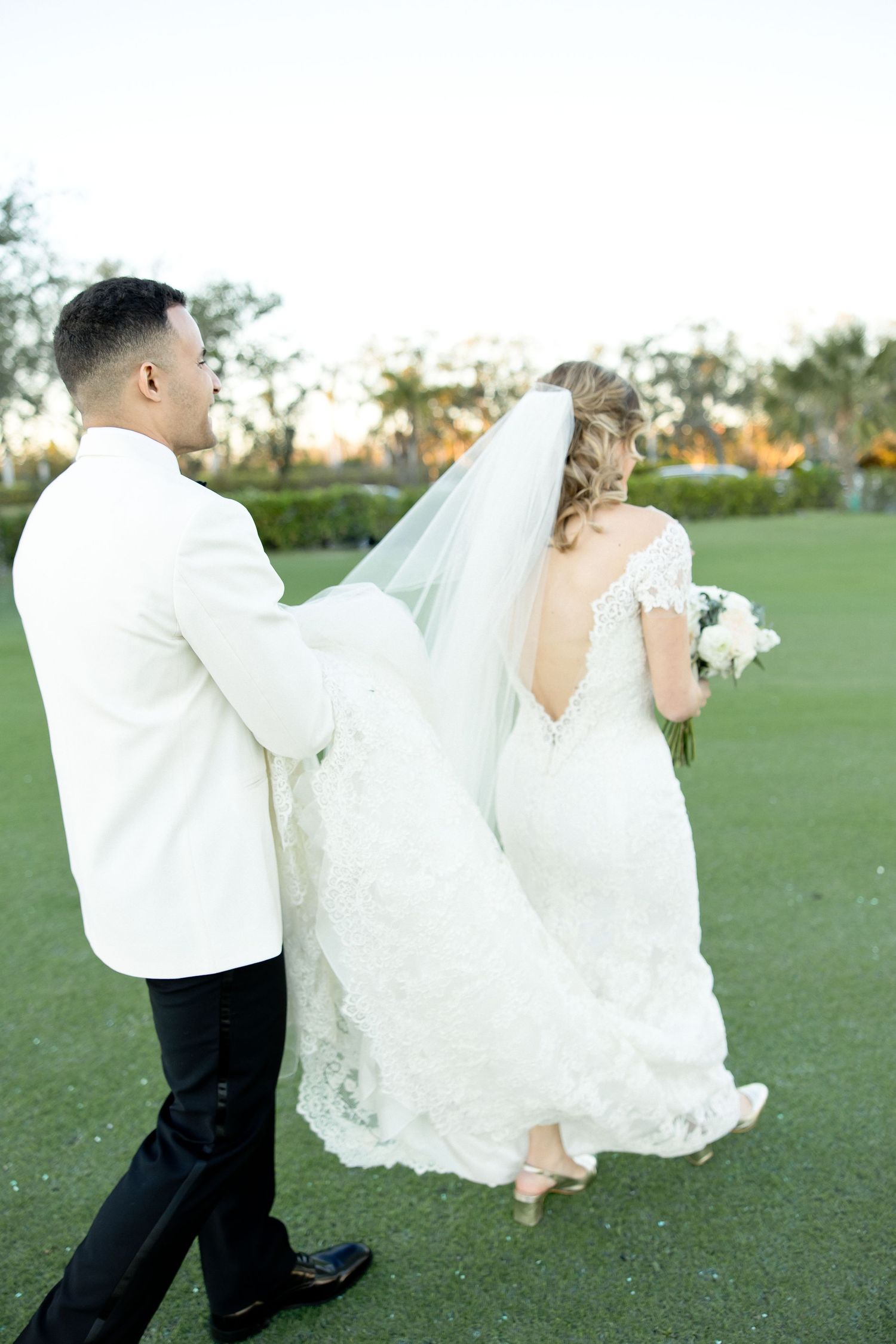 Couple dancing together on a green lawn at sunset.