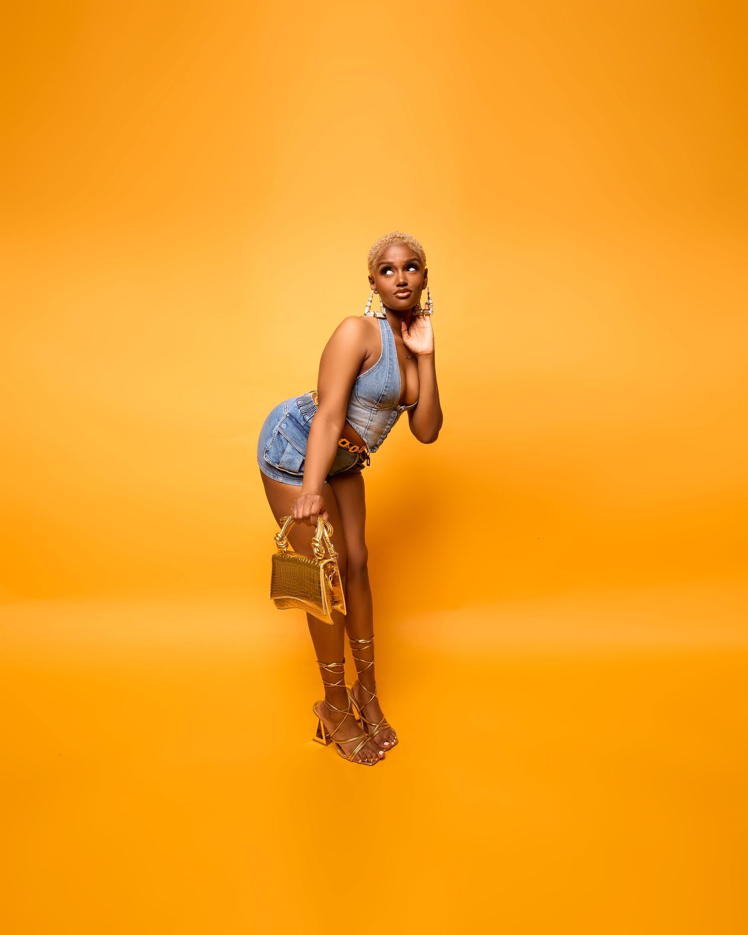 A figure in a denim outfit strikes dynamic poses against a vibrant orange background in a photo sequence.