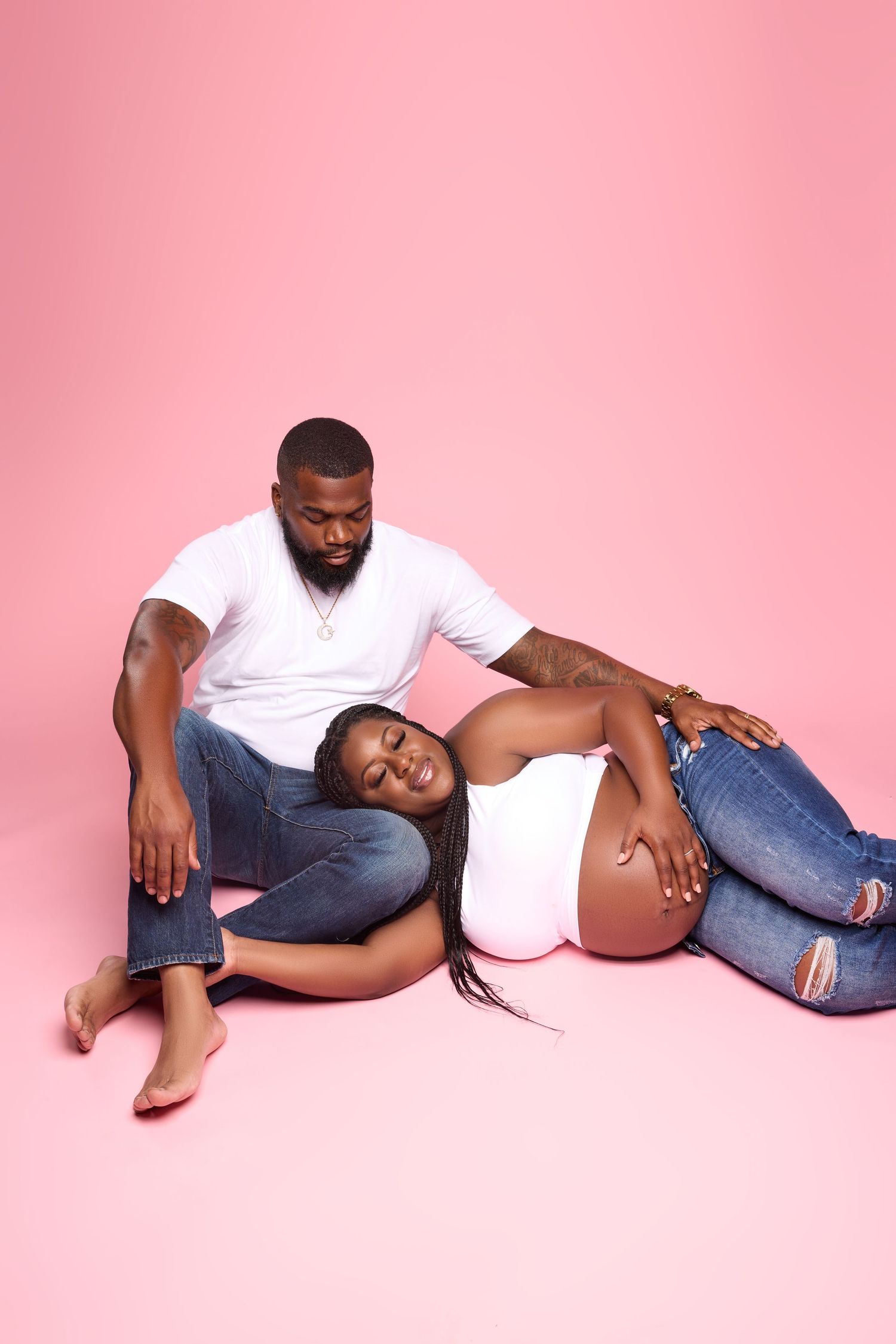 Casual maternity poses on pink background featuring comfortable denim and white clothing.