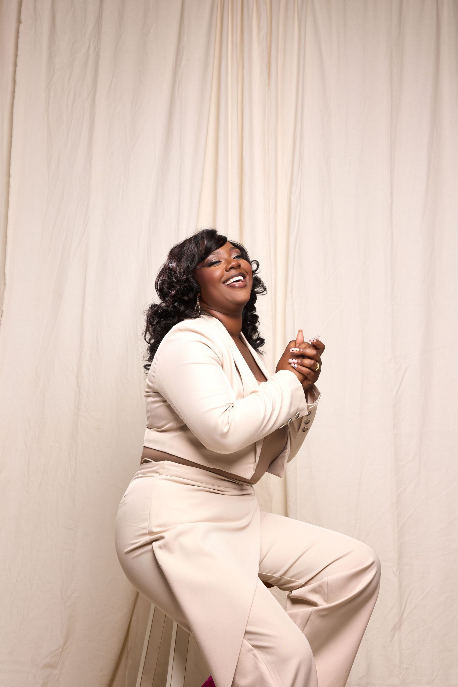 Joyful portrait series in cream outfit against white curtain backdrop showing natural expressions.