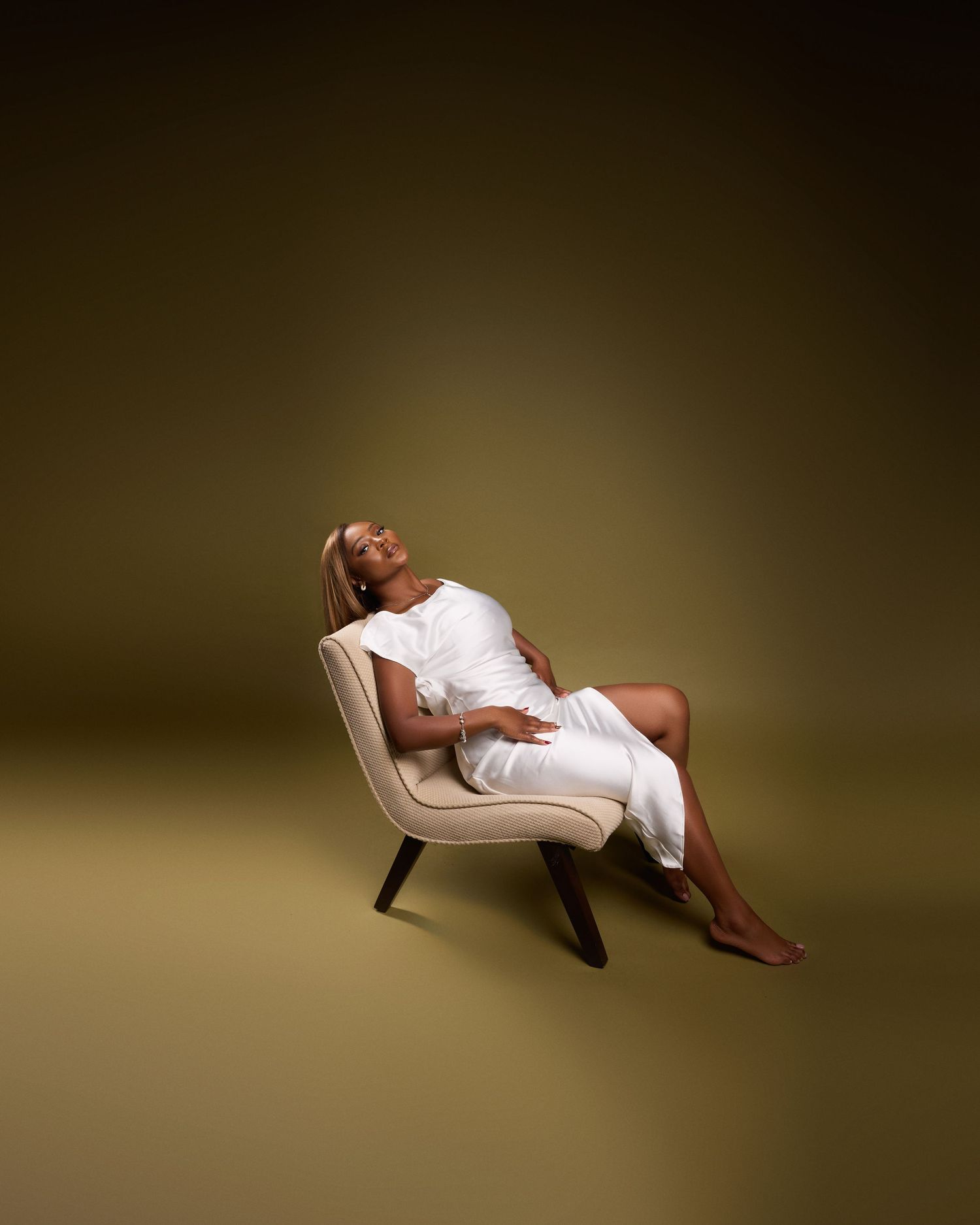 Artistic photo series showing model in white dress reclining on white chair with dramatic lighting.