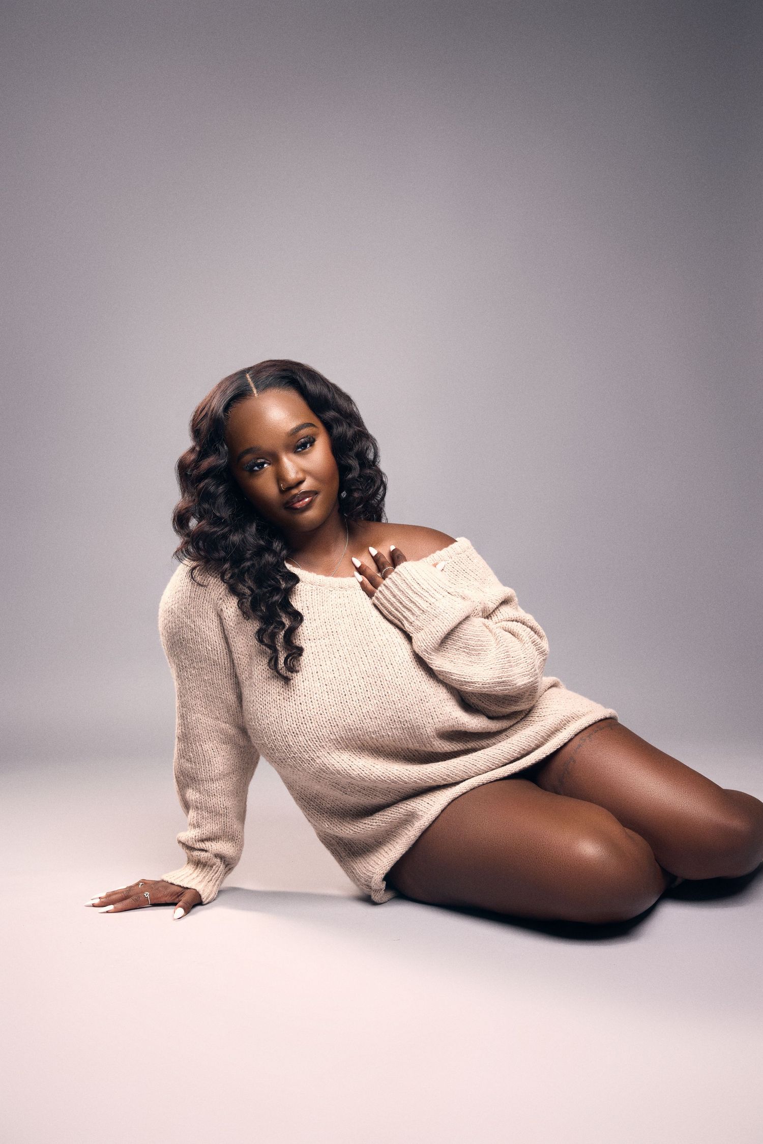 Cozy cream sweater fashion shoot against neutral grey studio background.