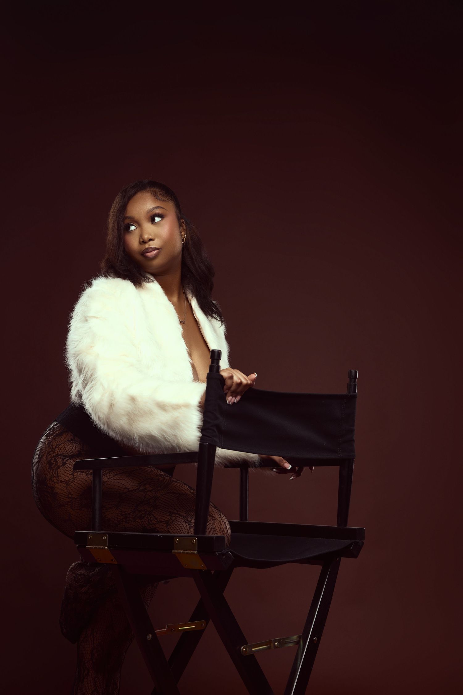 Artistic portrait series on director's chair with white fur stole against dark background.