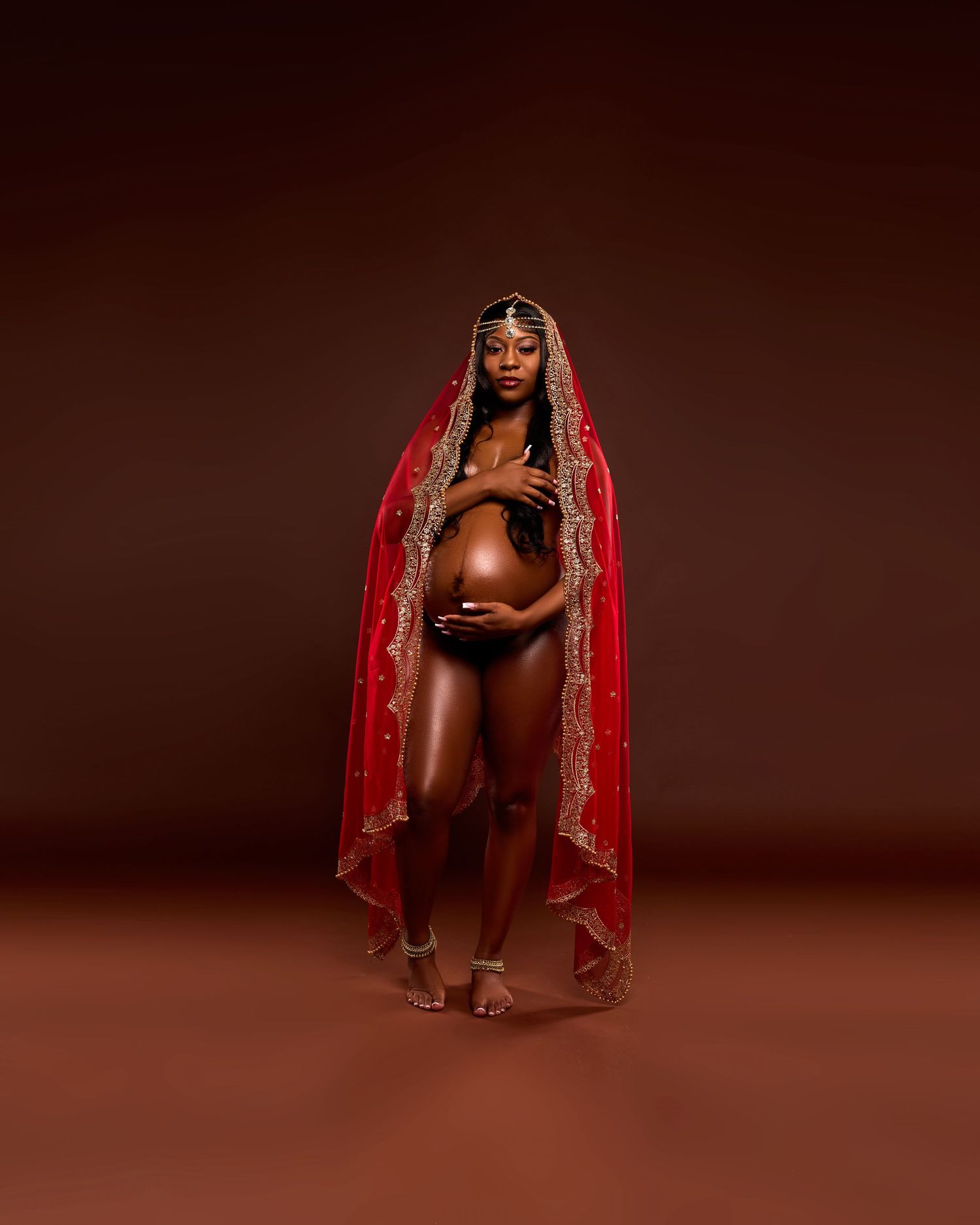 Elegant boudoir photoshoot with red traditional Indian dupatta against brown backdrop.