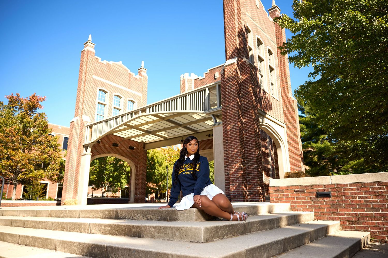 A student relaxes on stone steps in front of a Gothic-style university archway.