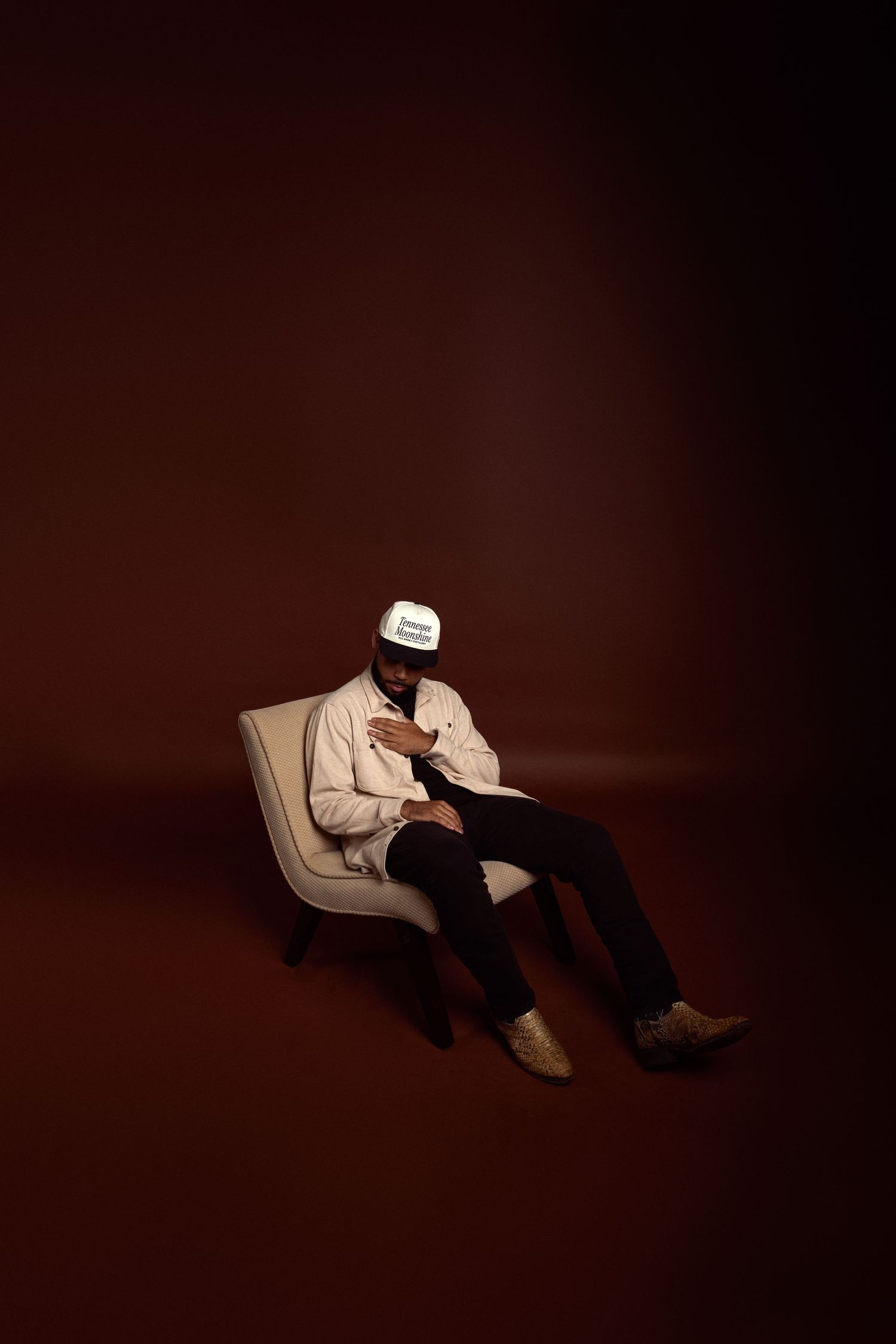 Person in light colored clothing lying down dramatically against dark background.