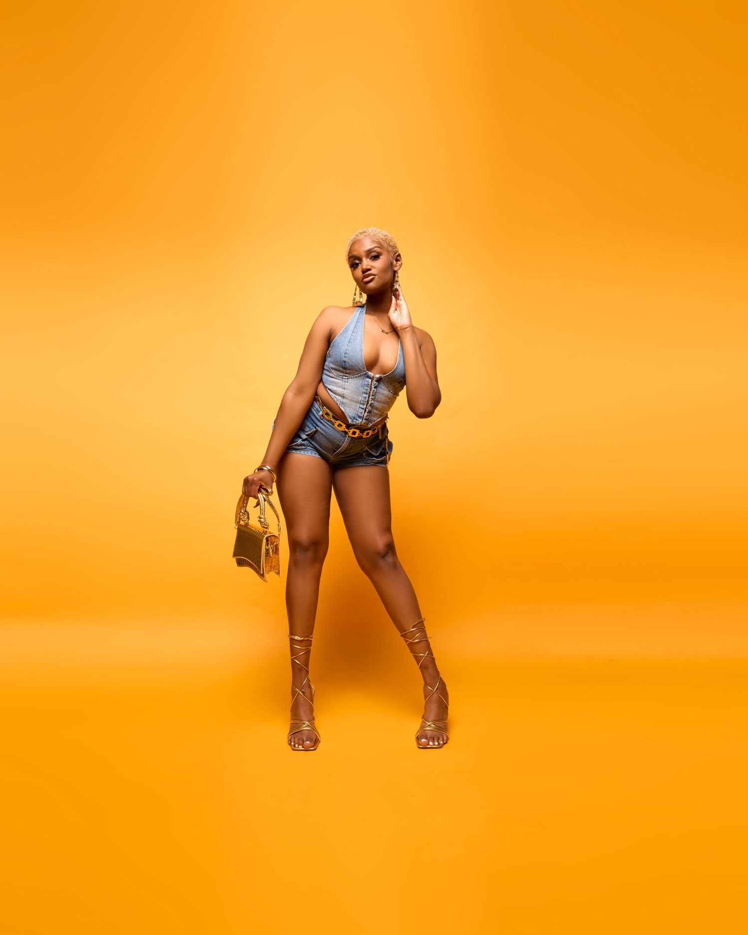 Fashion model in silver outfit poses against vibrant orange backdrop in dynamic series.