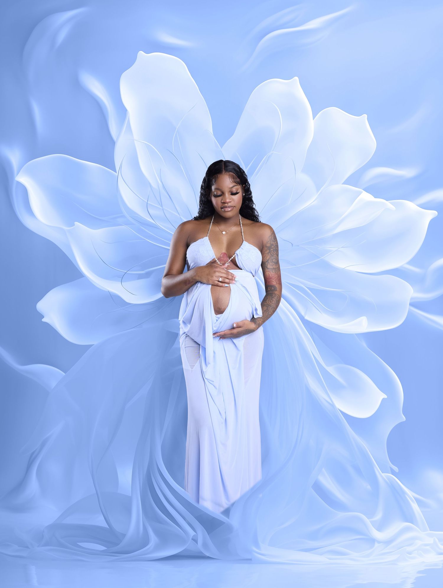 Pregnant woman in white draped gown poses gracefully against a soft blue background with a large white floral design.