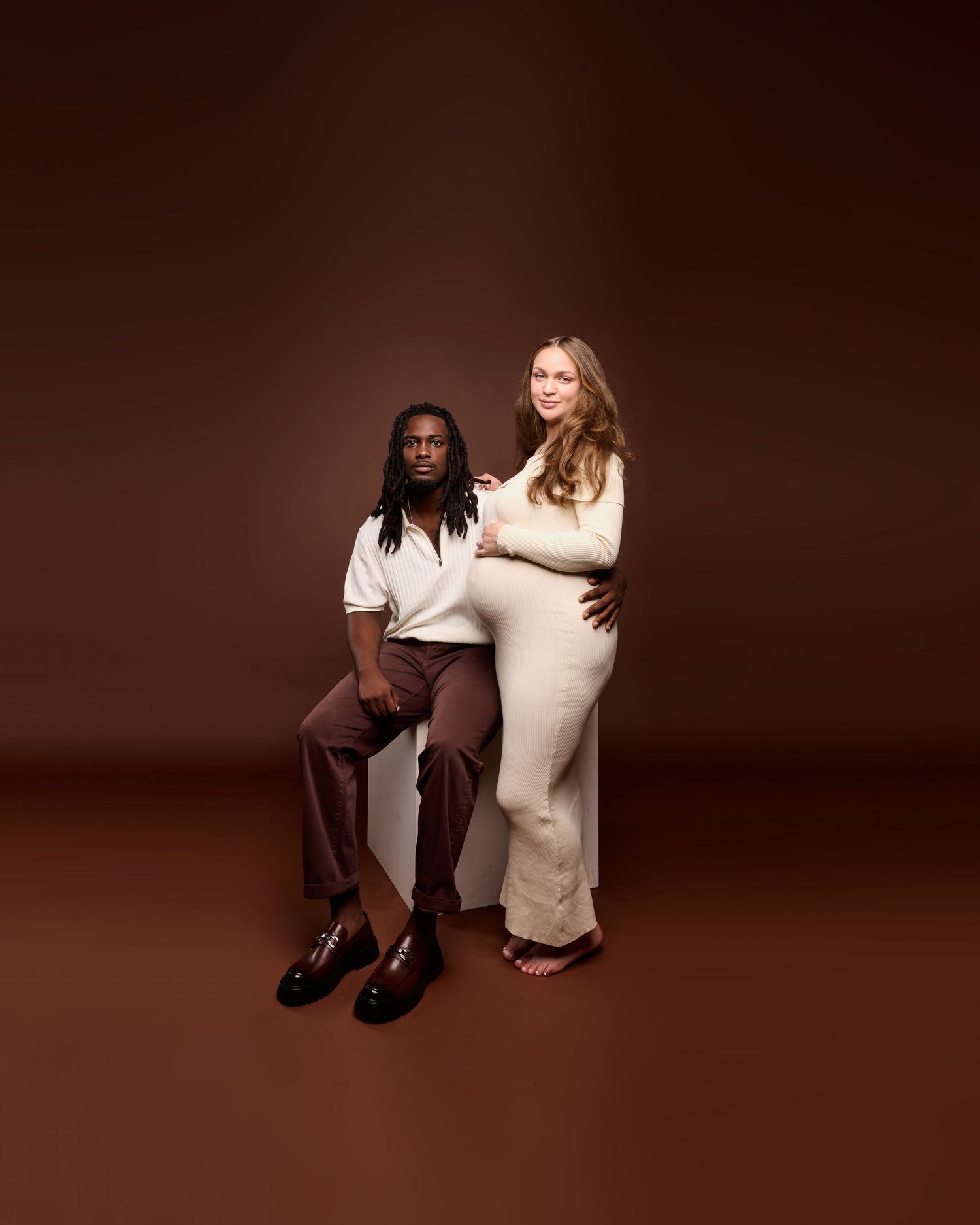 Studio portraits featuring couple in cream and brown outfits against dark background.
