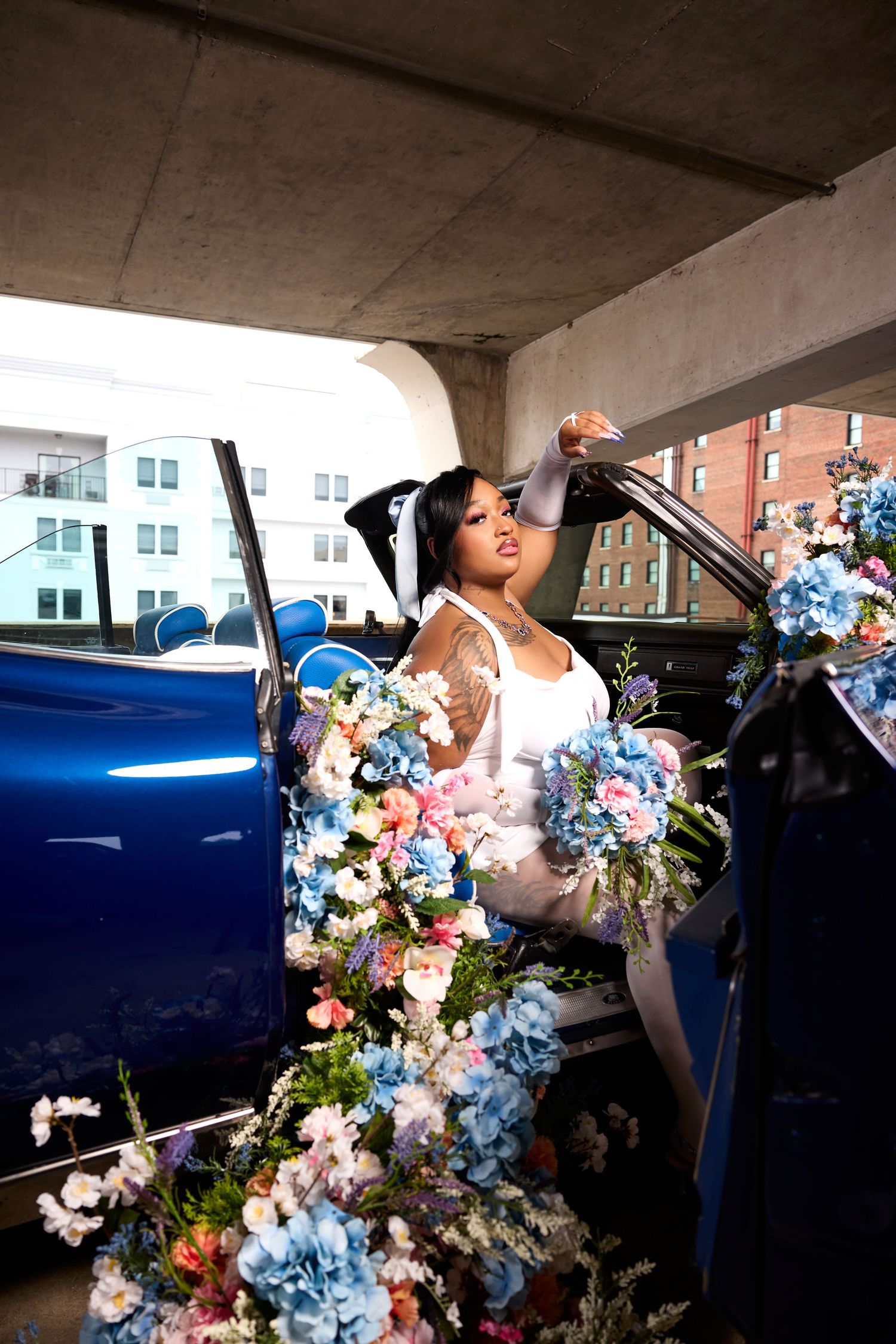 Creative graduation photos with vintage blue car decorated with colorful floral arrangements.