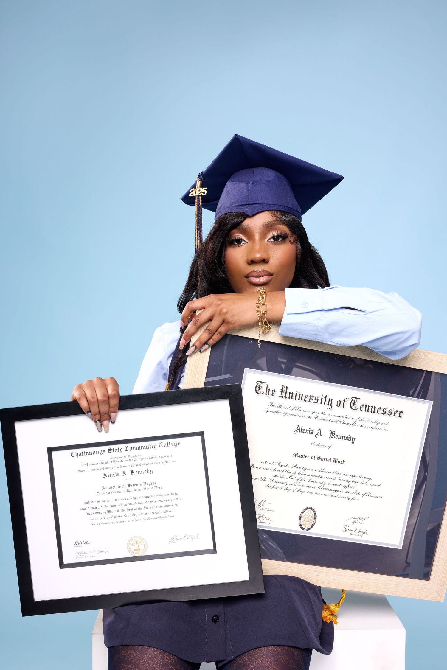 Graduate displays multiple academic certificates and diplomas against blue backdrop.