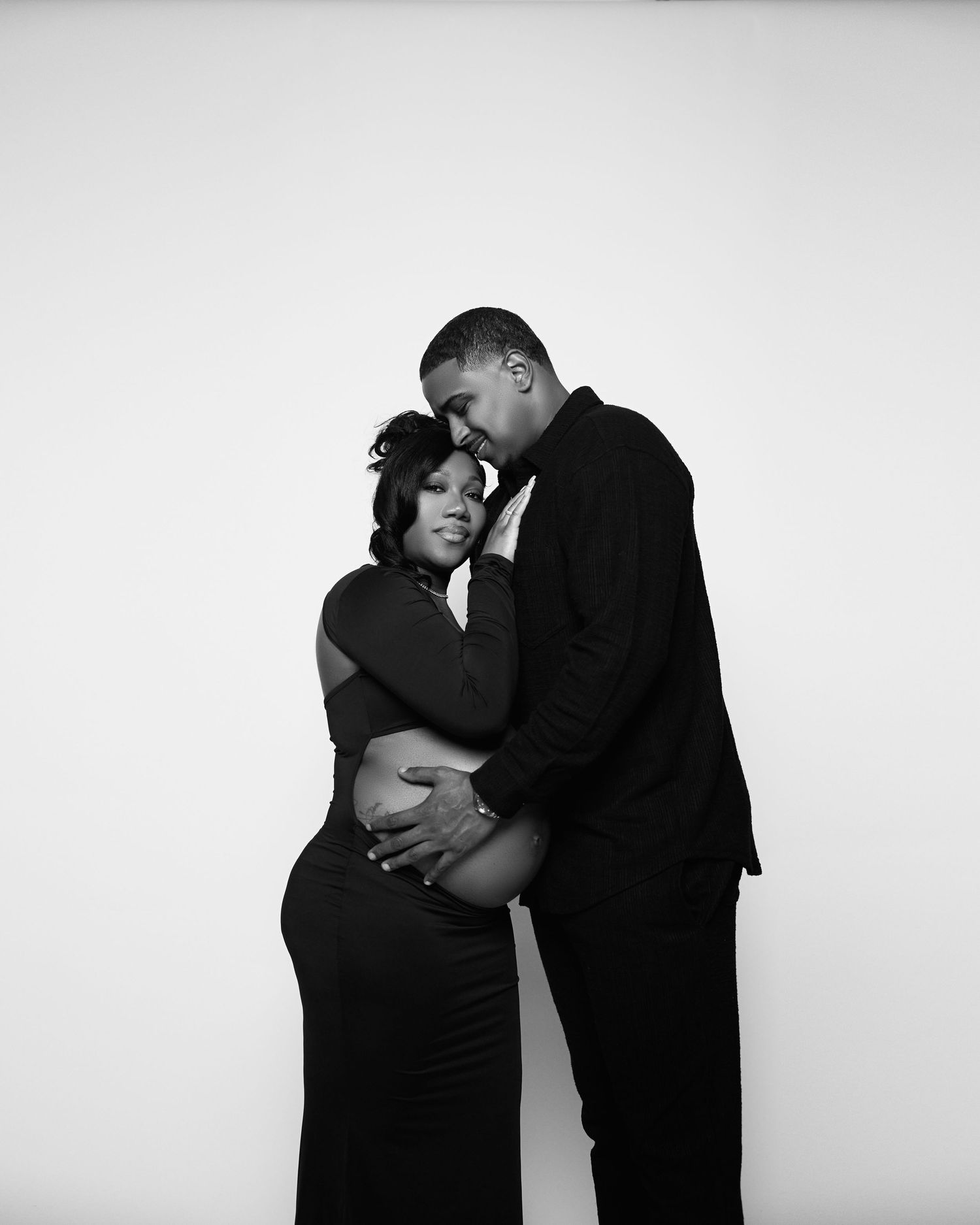 Artistic black and white maternity portrait series against white backdrop.