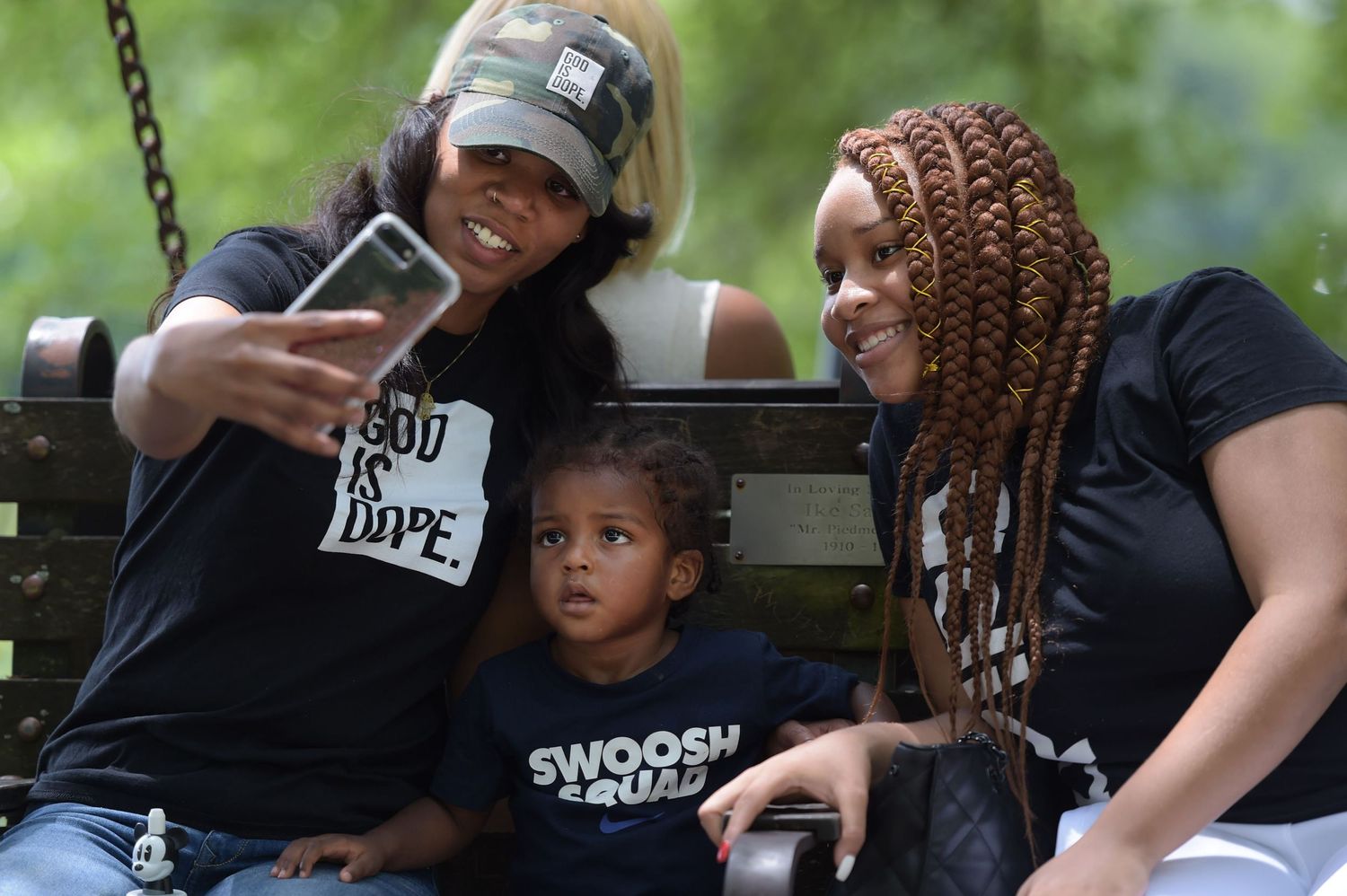 Family sitting together on a park bench looking at a mobile phone.