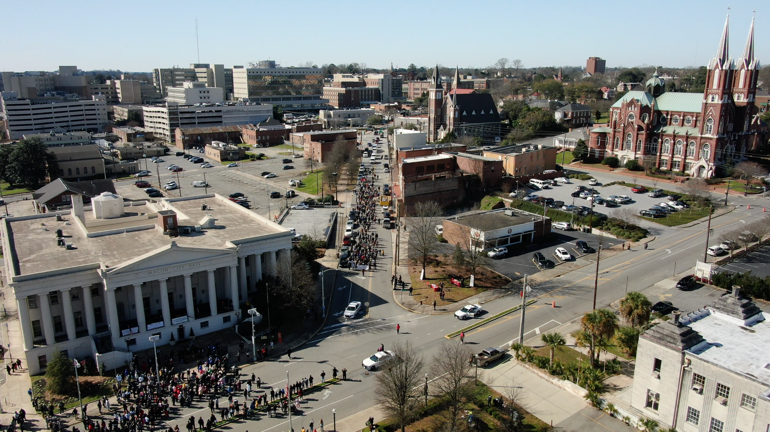 Bird's eye view of downtown area during a Martin Luther King Jr. Day march showing historic buildings and a crowd gathered on the street.