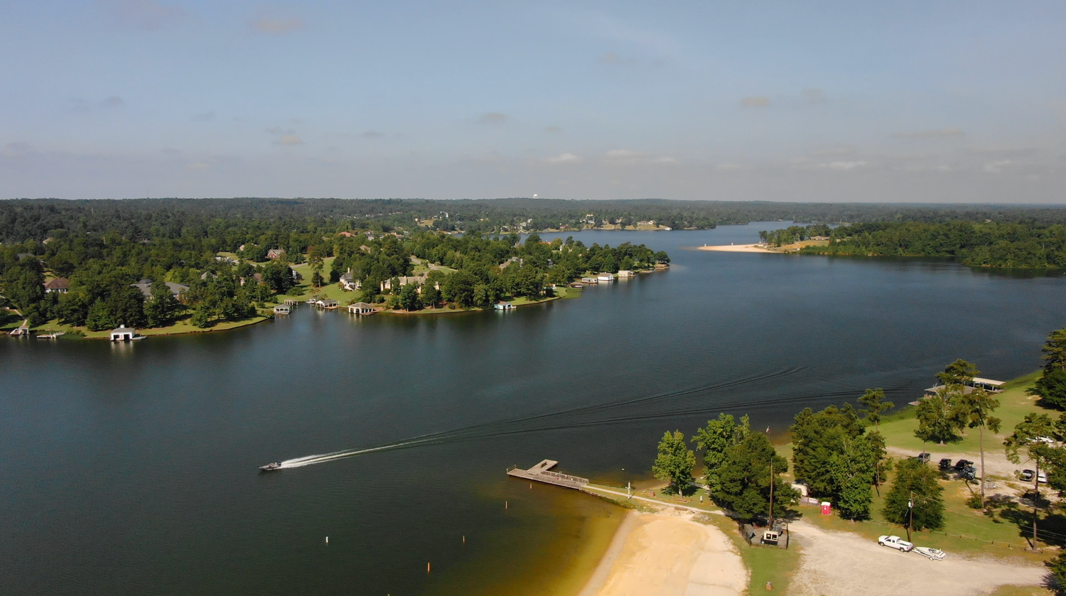 Aerial view of lakeside peninsula with beaches, boats, and wooded shoreline.