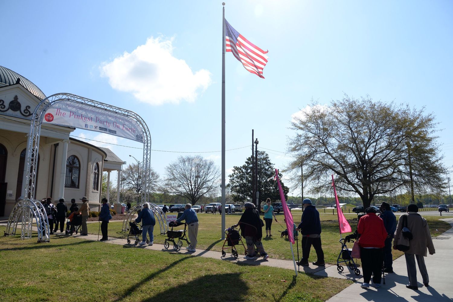 People gathering outside a building with an American flag flying in the breeze.