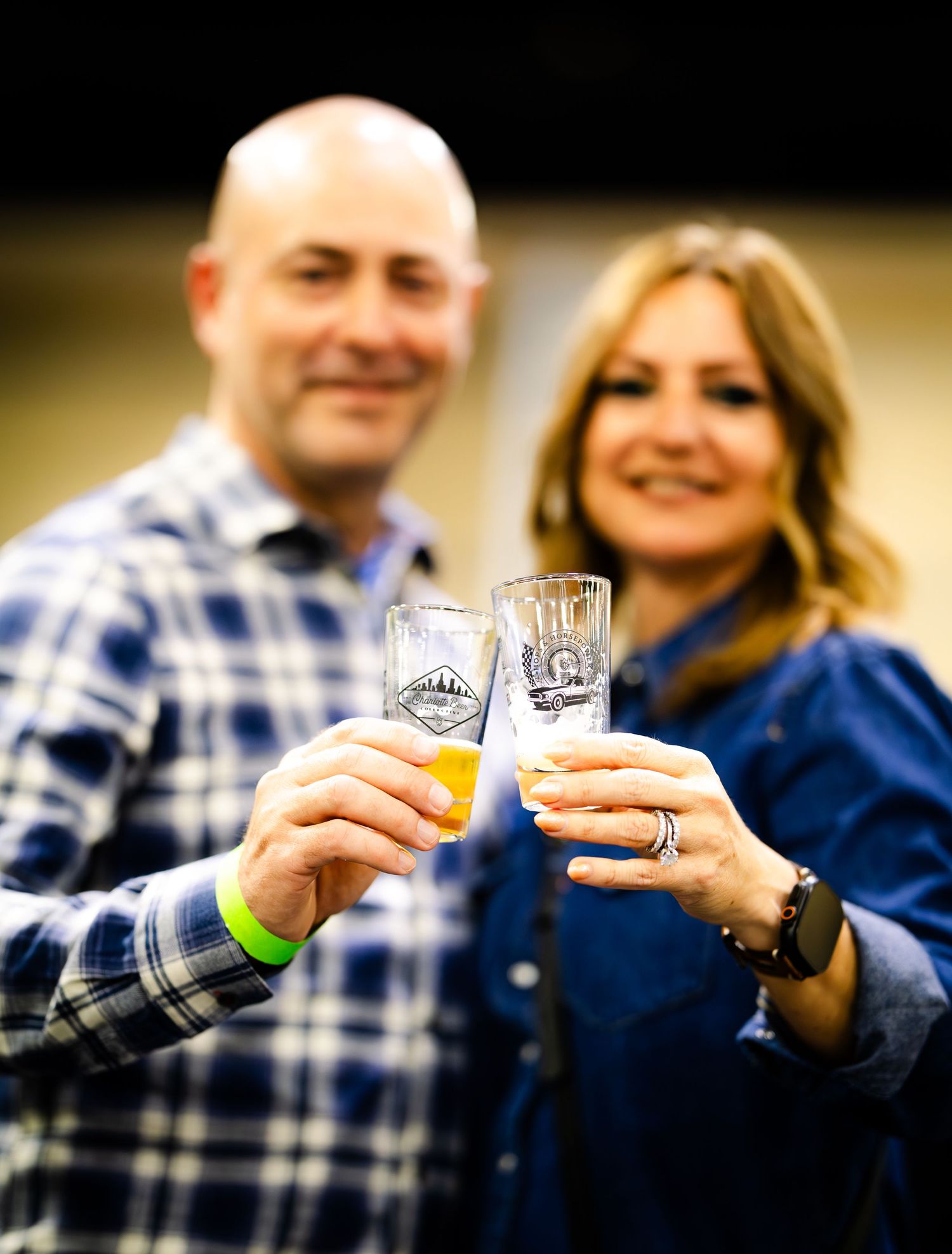 A couple toasts with beer glasses at an outdoor celebration.
