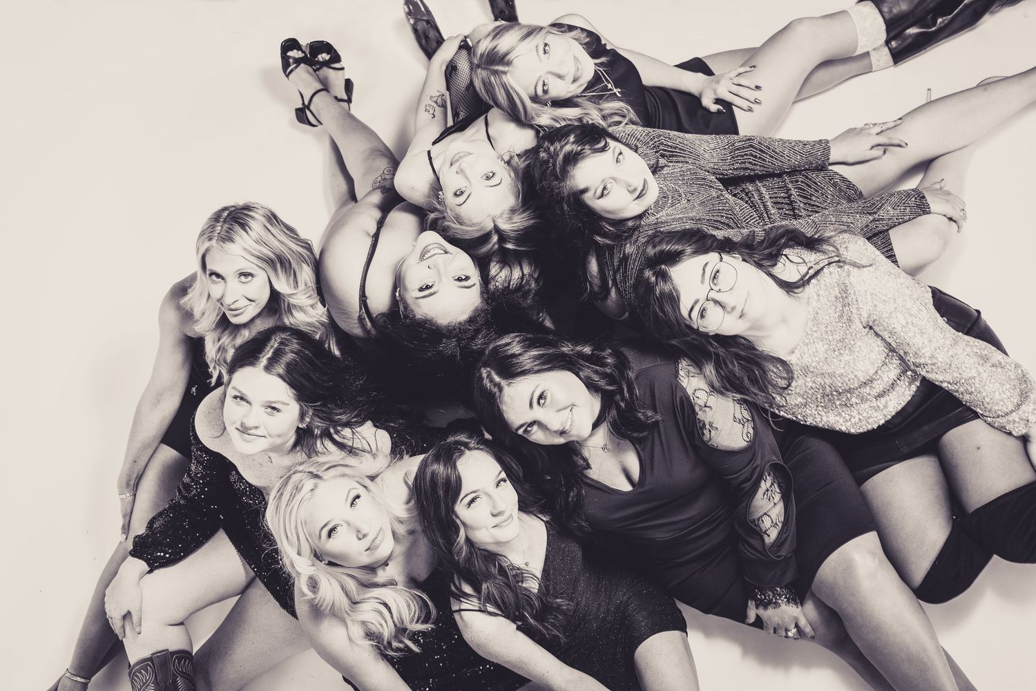 An artistic overhead black and white photo of friends lying in a circular formation.