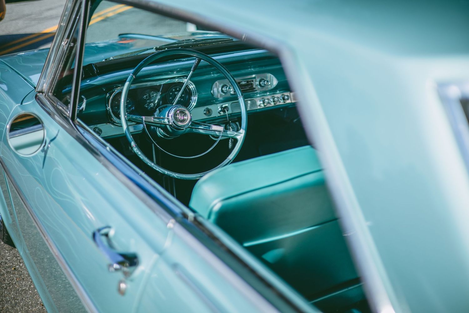 Interior dashboard view of a classic car showing vintage steering wheel and gauges.