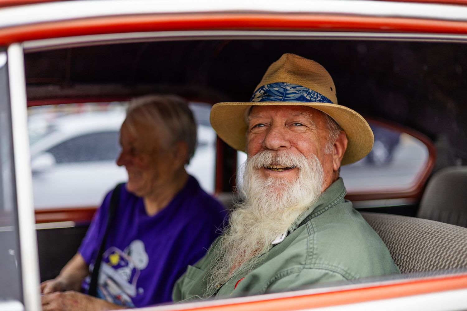 Classic car enthusiasts gathered around vintage vehicles at an outdoor show.
