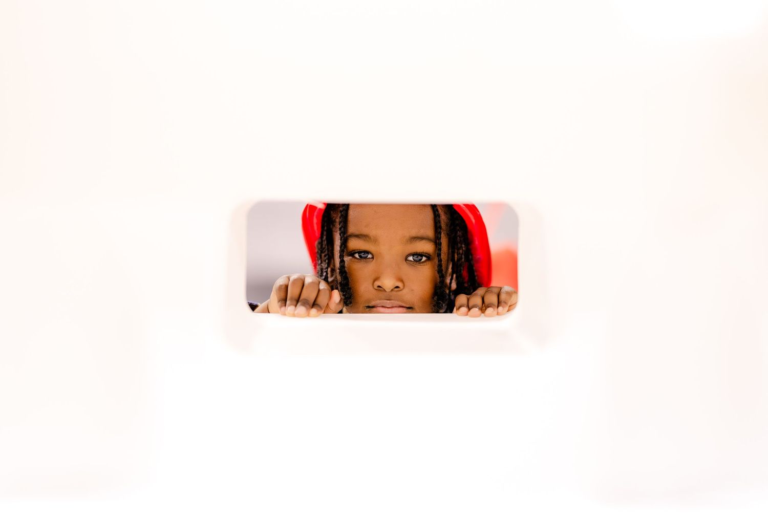 Partial view of faces peeking through a white surface.